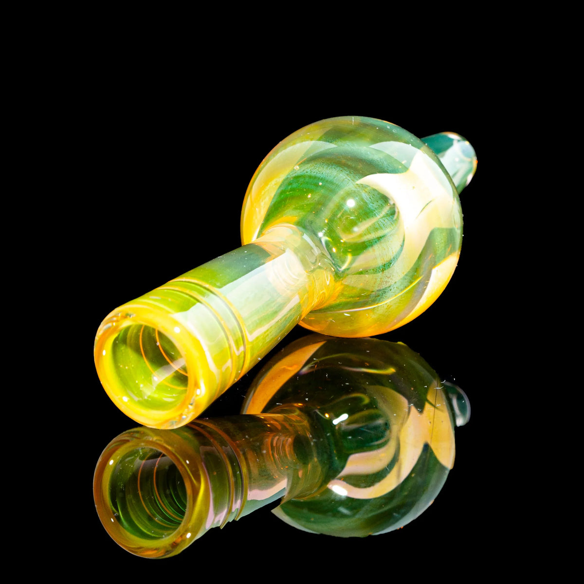 Yellow and green glass hand pipe with reflective black background