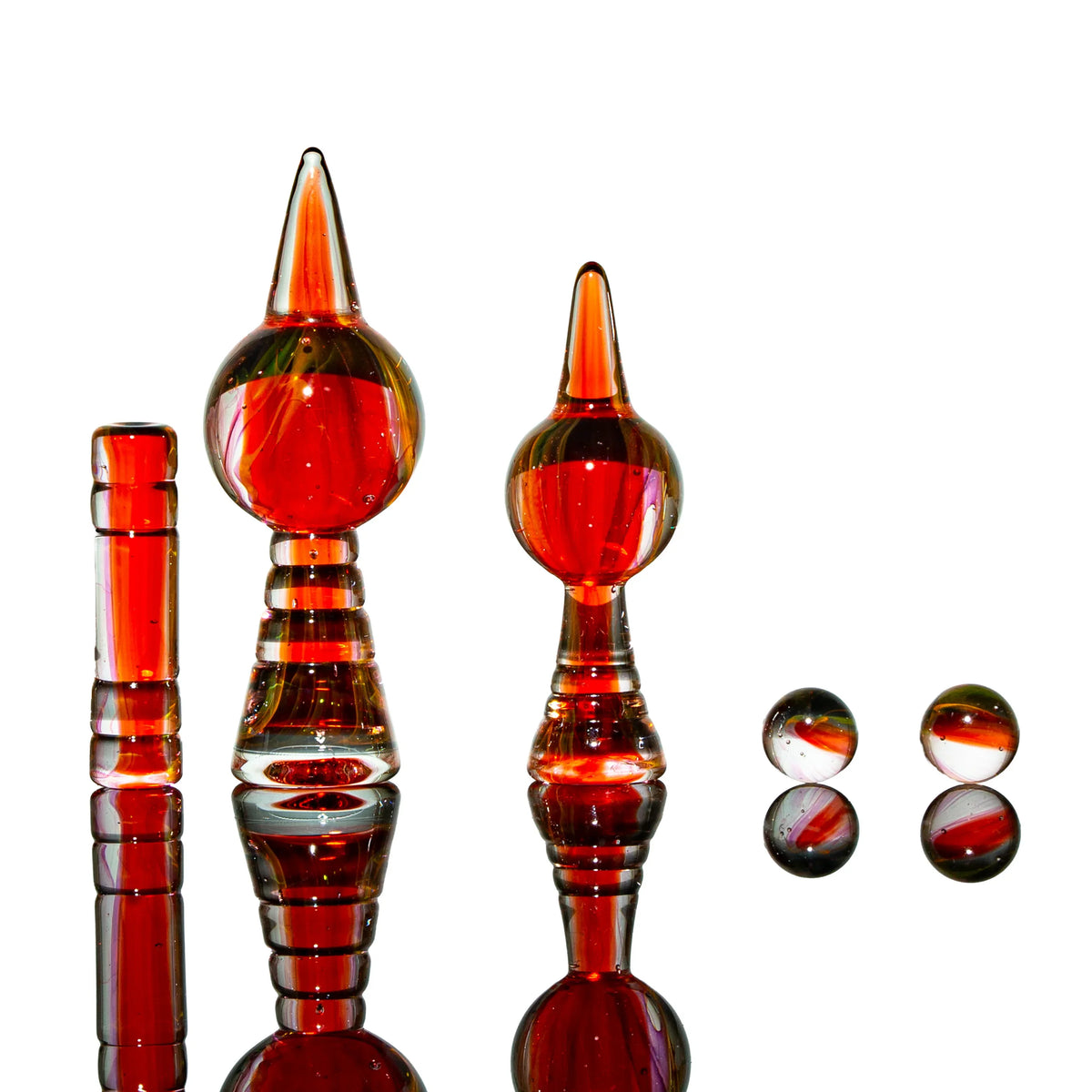 Red glass dab tool set with pointed carb caps and marbles on white background