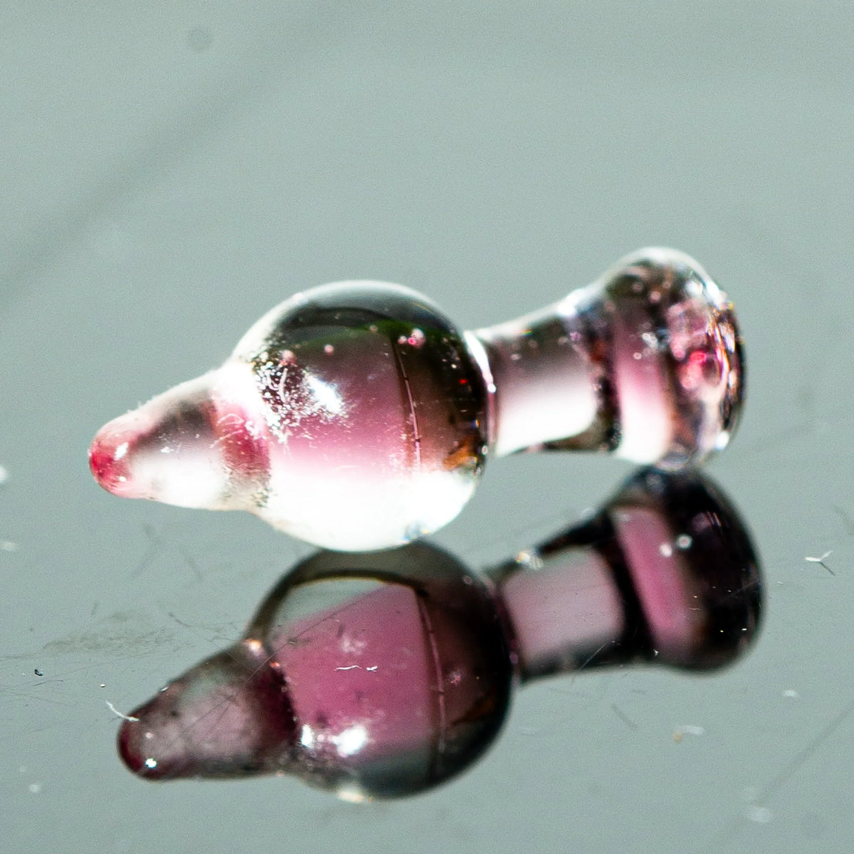 Pink glass carb cap accessory for dab rig on reflective surface