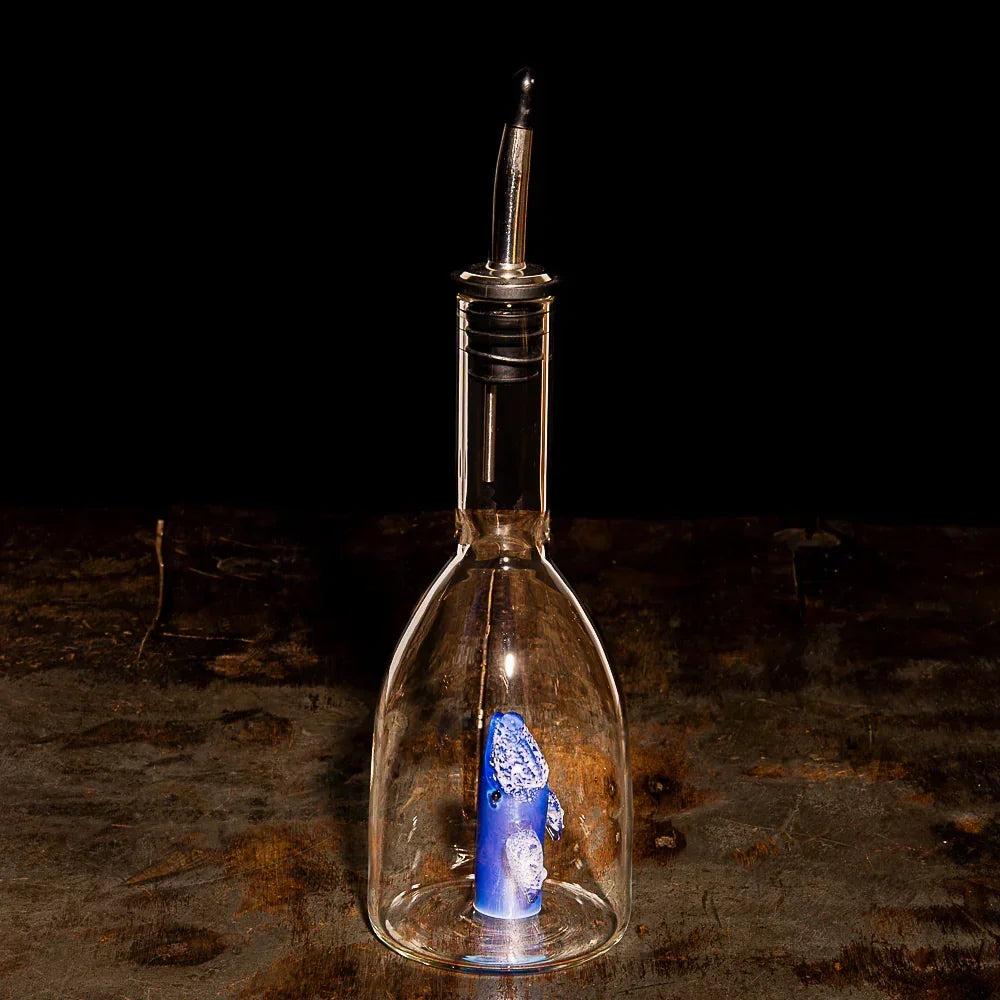 Glass dab rig with blue percolator on rustic wood table, smoke shop accessory