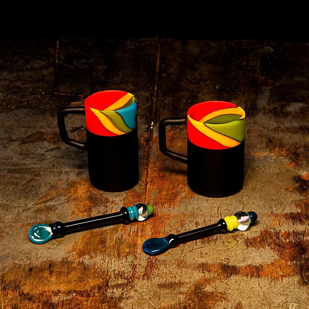 Colorful glass mugs and glass dab tools on a rustic wooden surface