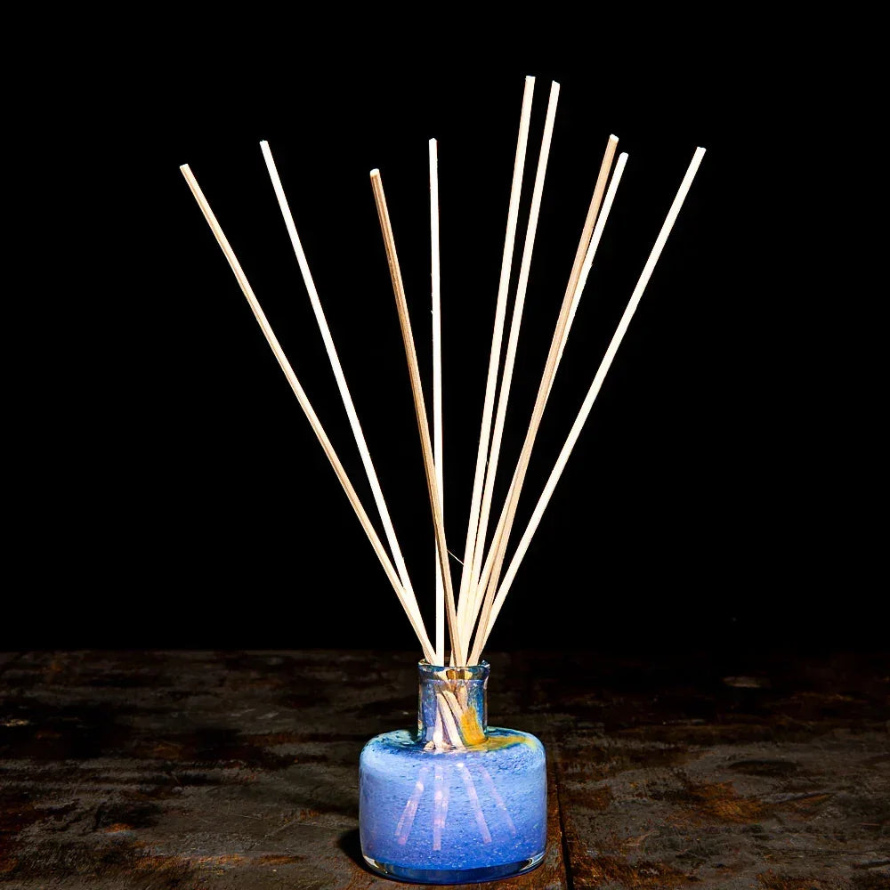 Wooden diffuser sticks in a blue glass jar on a dark rustic surface