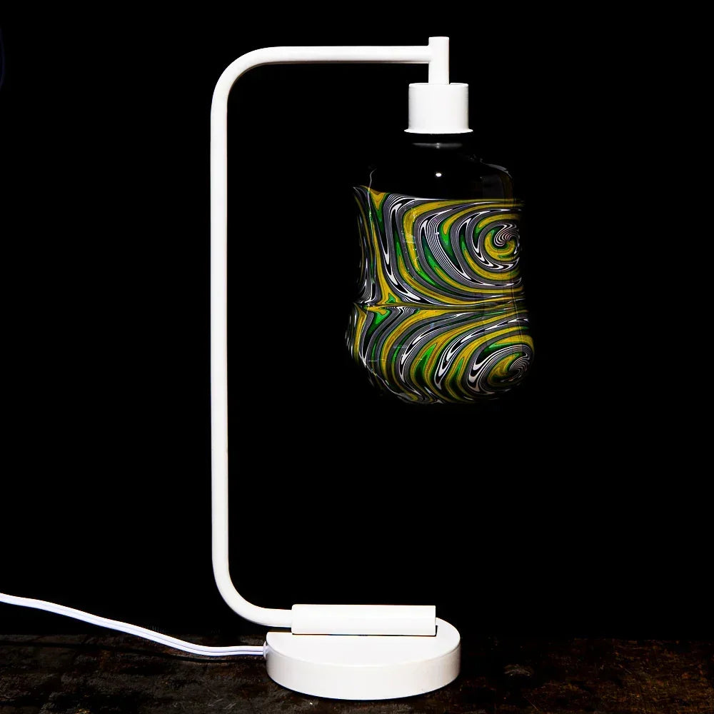 Colorful heady glass art piece with green and yellow swirls on white stand, black background