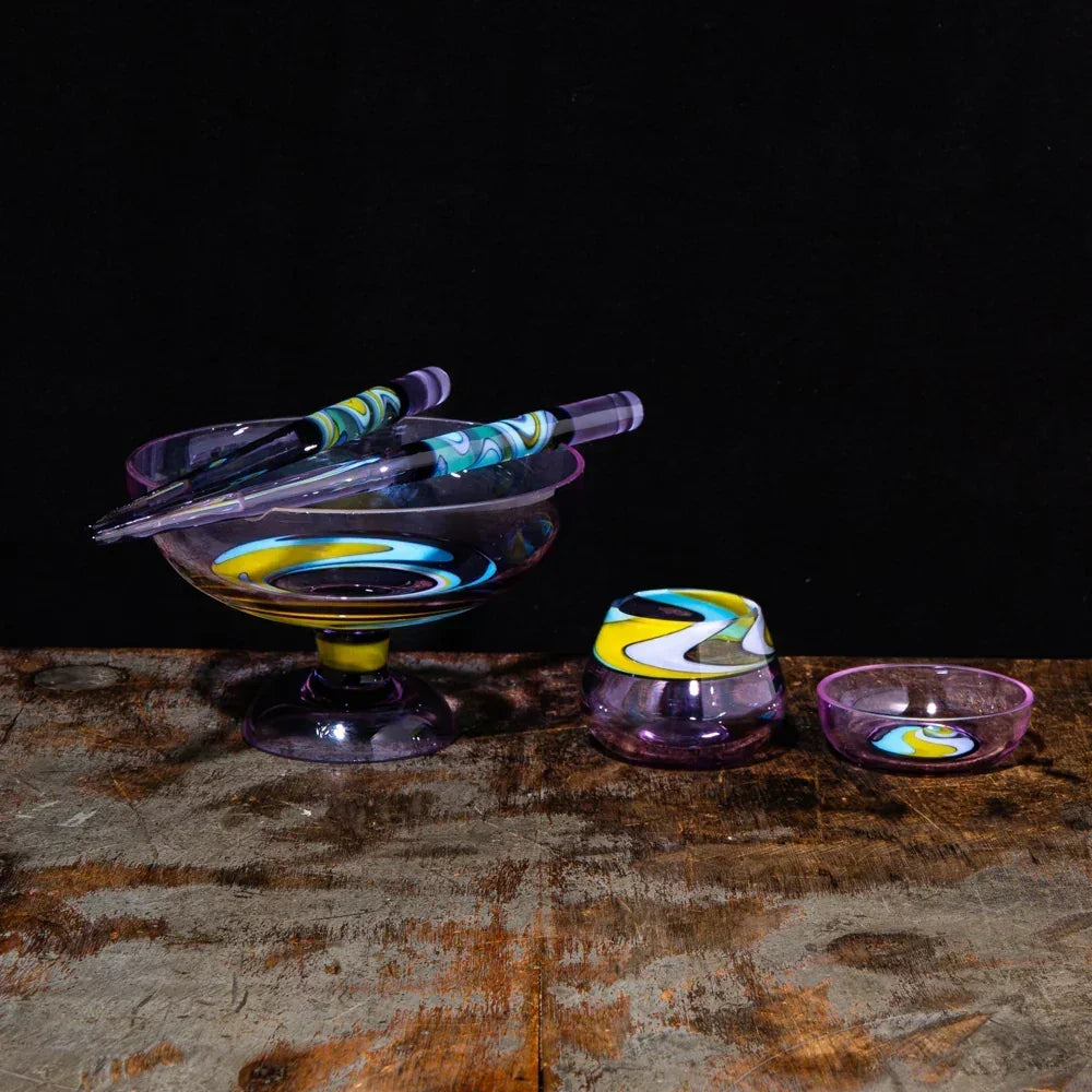 Hand-blown glass smoking accessories with colorful swirl designs on a rustic wooden surface