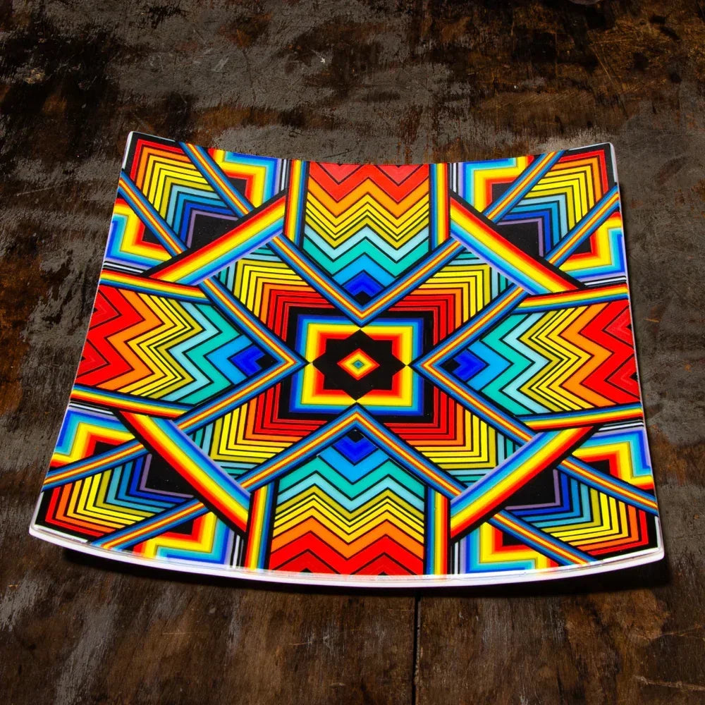 Colorful glass tray with geometric rainbow pattern on a wooden surface