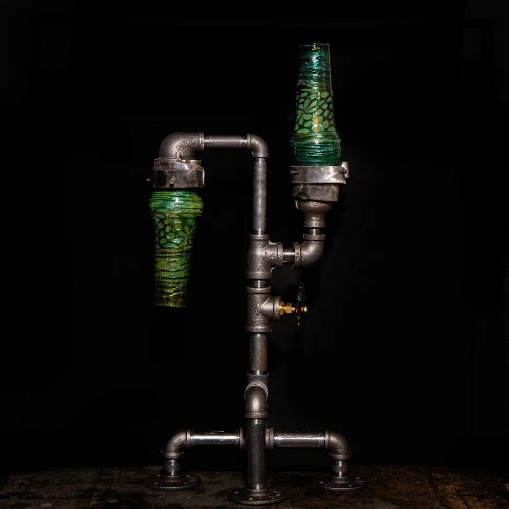 Industrial style glass water pipe with green accents and metal fittings on dark background