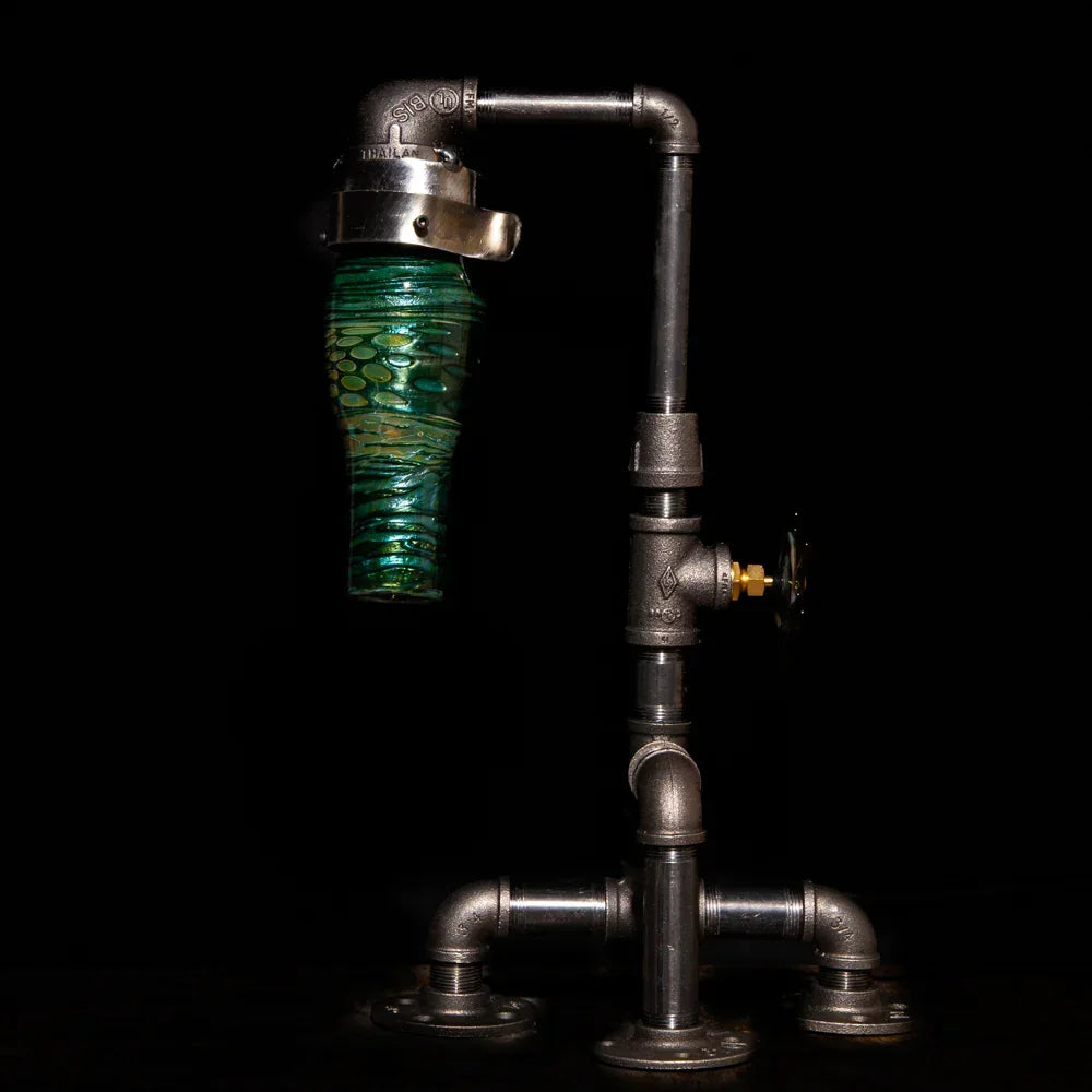 Industrial-style glass pipe with green textured chamber and metal fittings on black background
