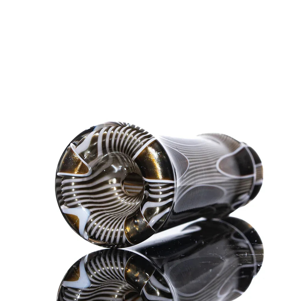 Handblown glass chillum with black, gold, and white swirls on reflective surface