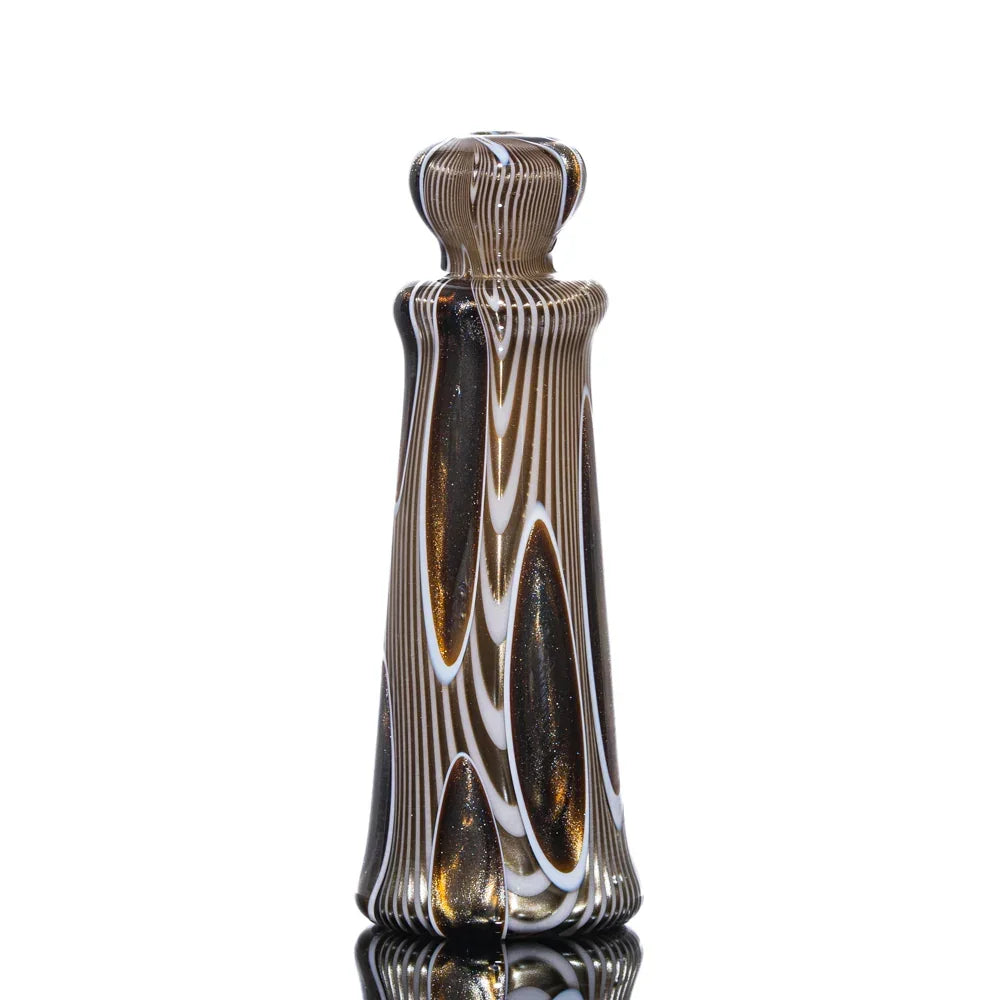 Handcrafted chillum with black, gold, and white glass swirl pattern on reflective surface