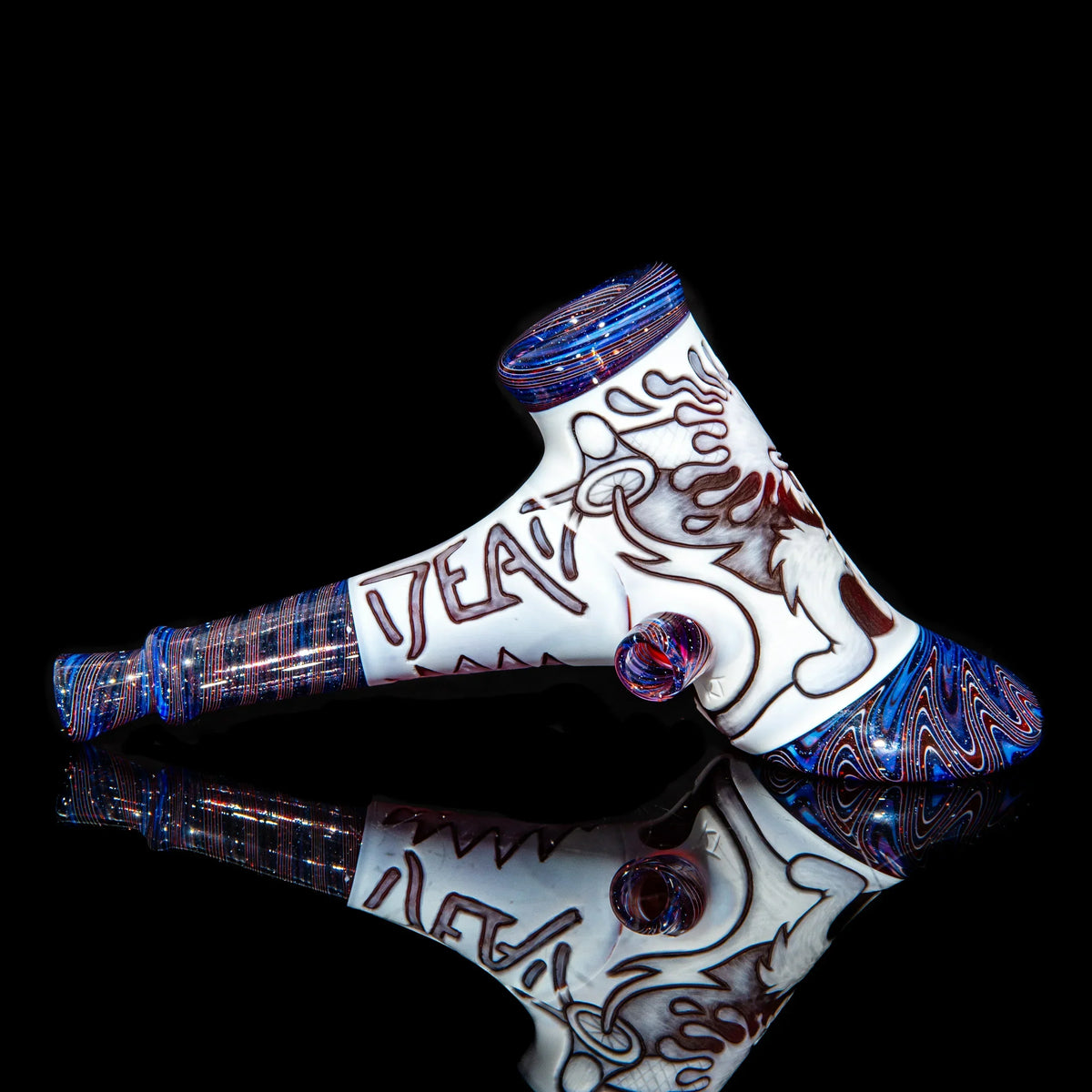 Heady glass hand pipe with bold red designs and blue accents on black background