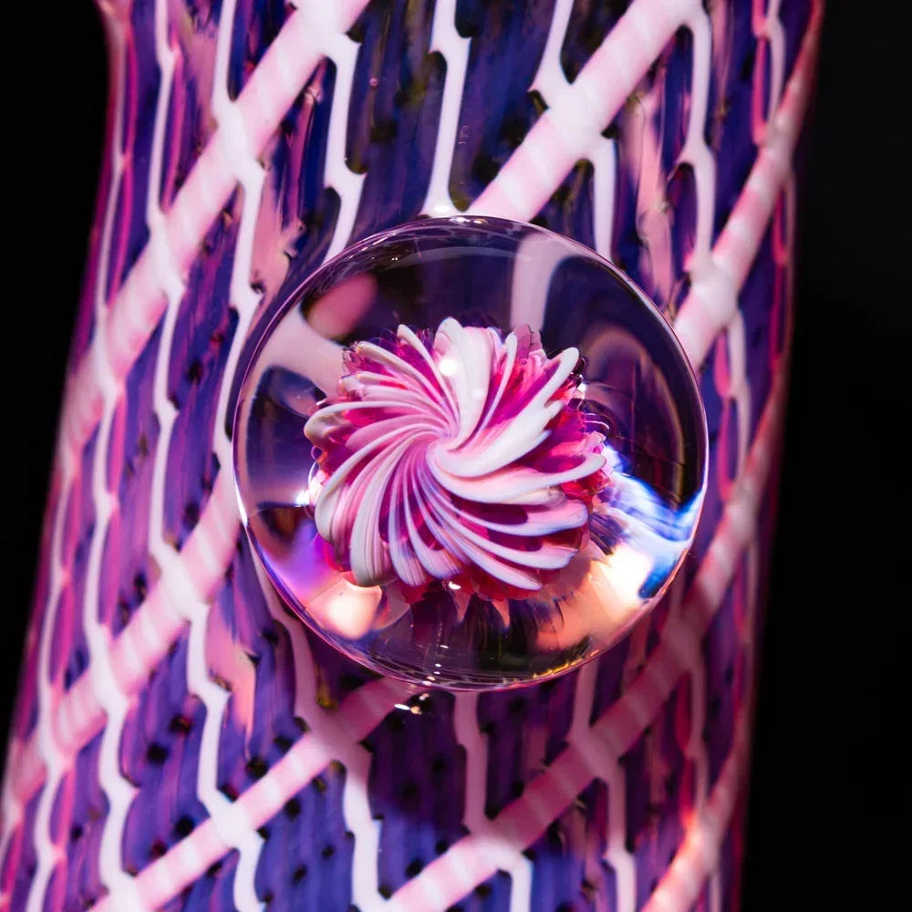 Close-up of colorful glass bubbler with vibrant honeycomb and seashell swirl design