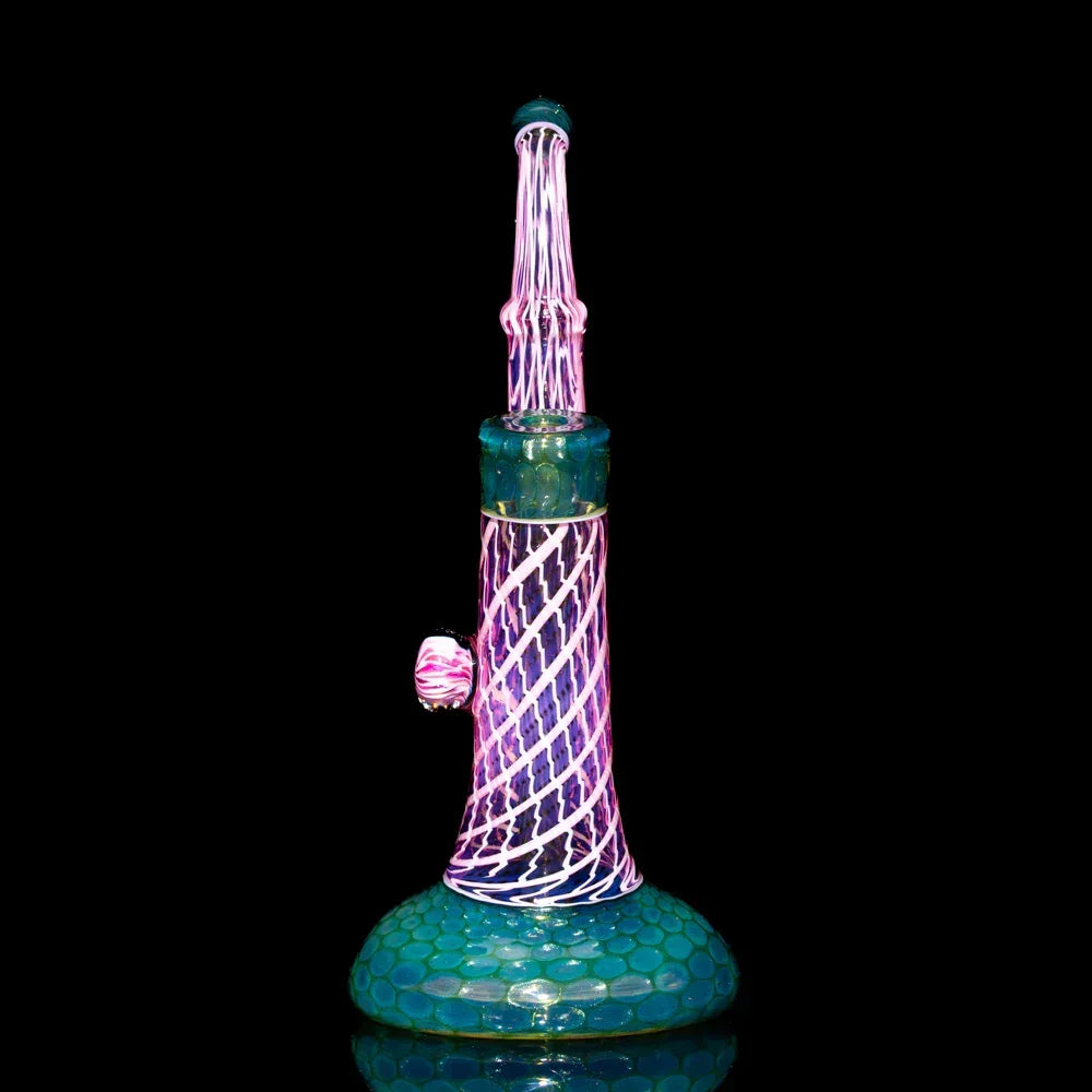 Heady glass bubbler with honeycomb and seashell patterns in pink and teal on black background