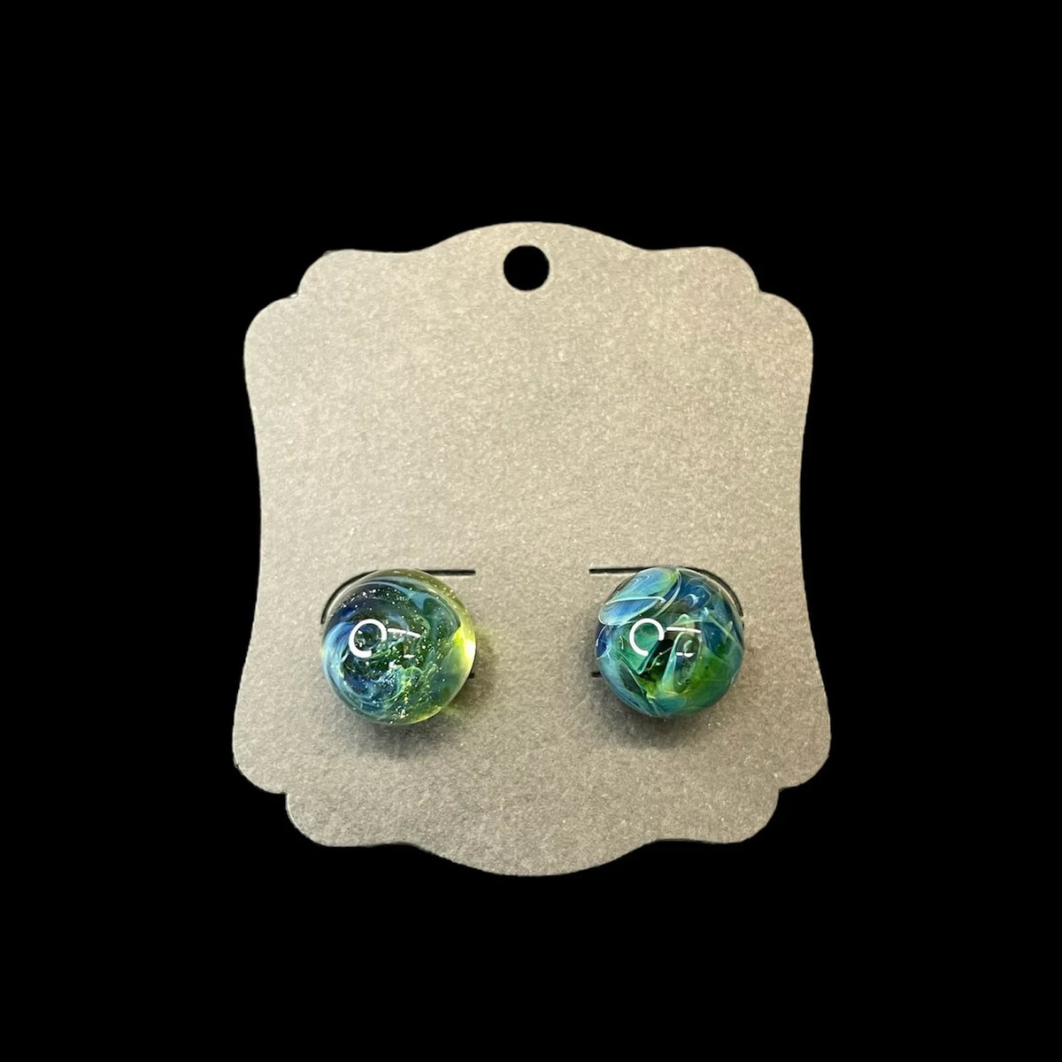 Handmade glass stud earrings with blue and green swirls on a gray display card