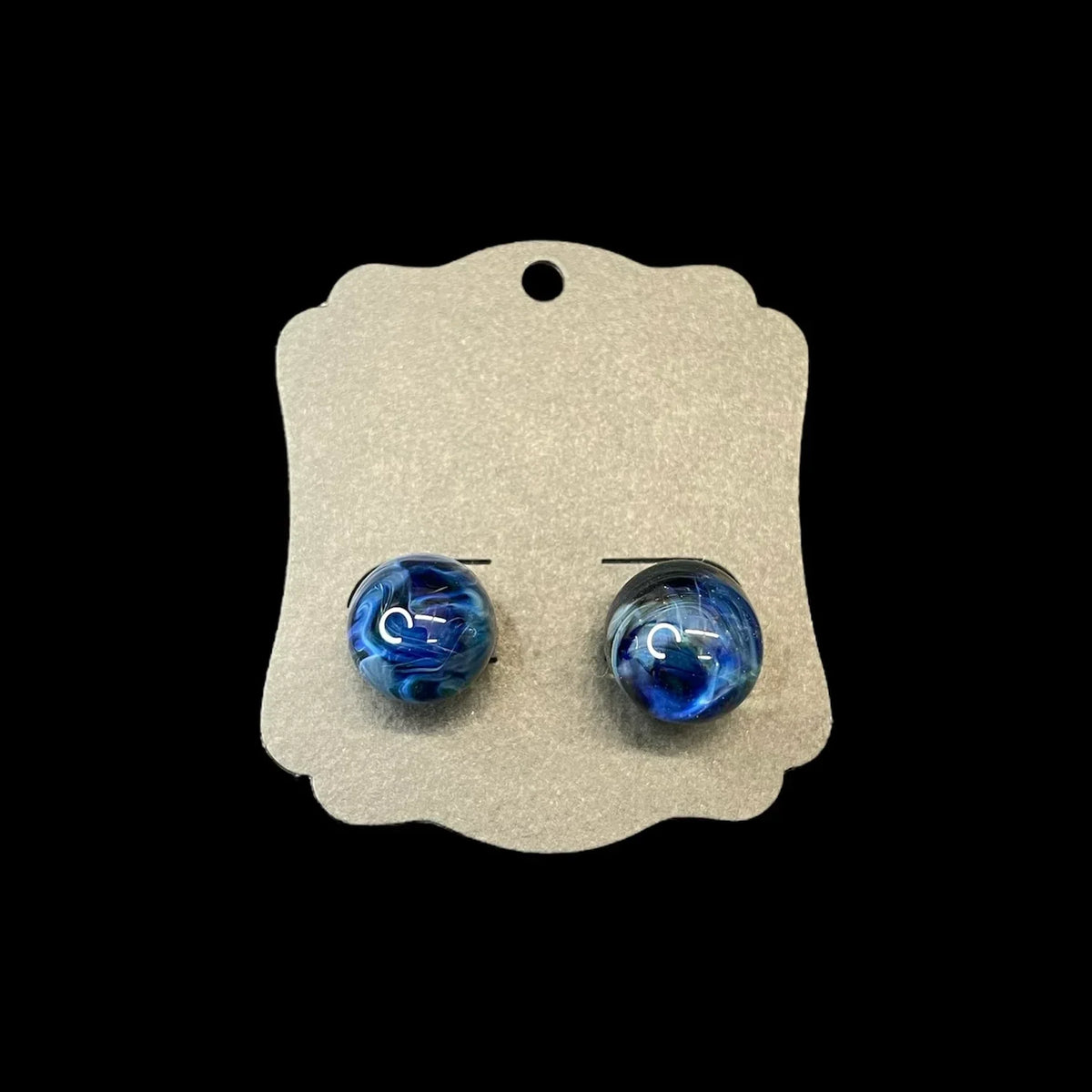Pair of round blue glass earrings with swirling patterns on display card