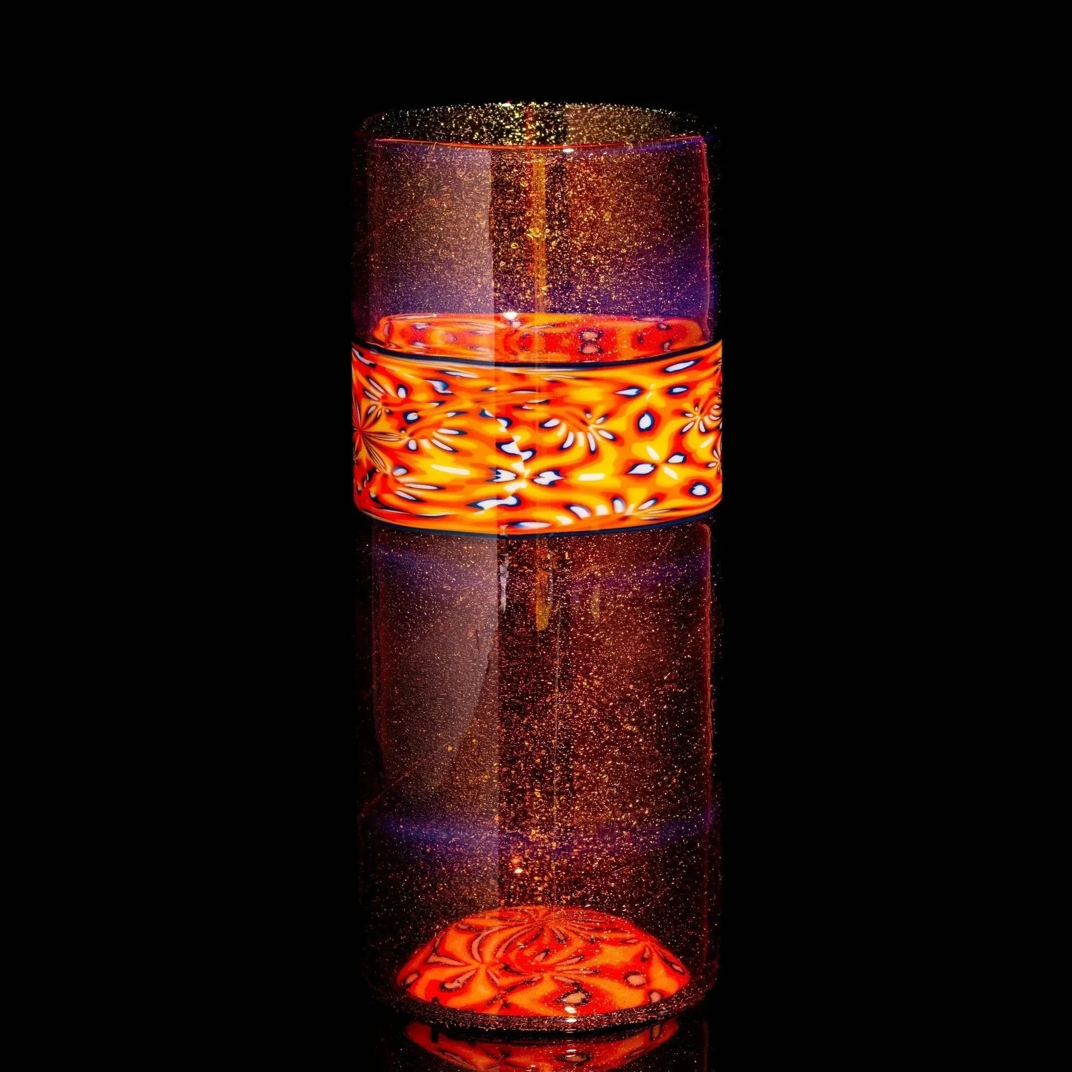 Handblown glass cup with orange and red patterned band, shimmering gold flecks, black background