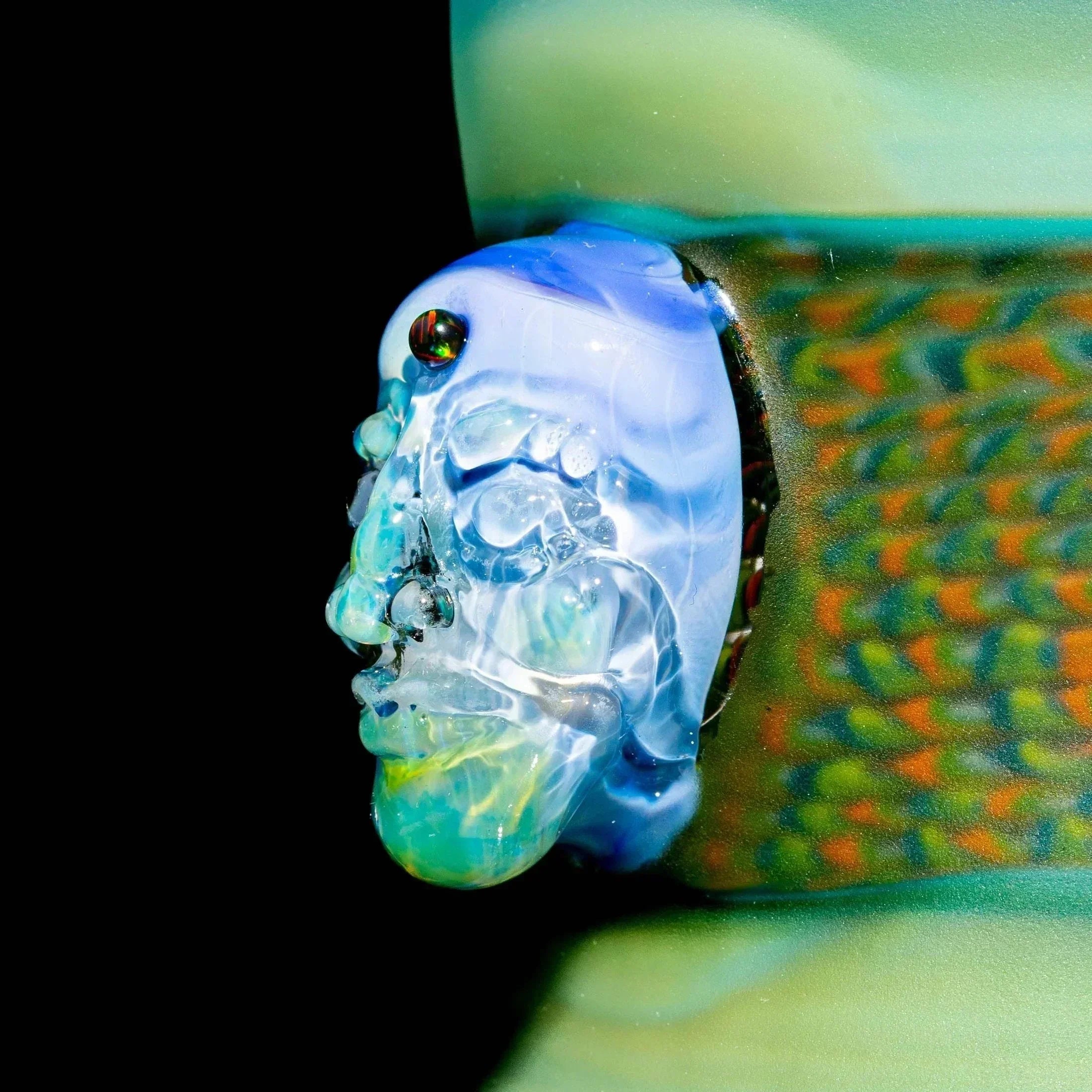 Close-up of intricate hand-blown glass art pipe with detailed sculpted face design