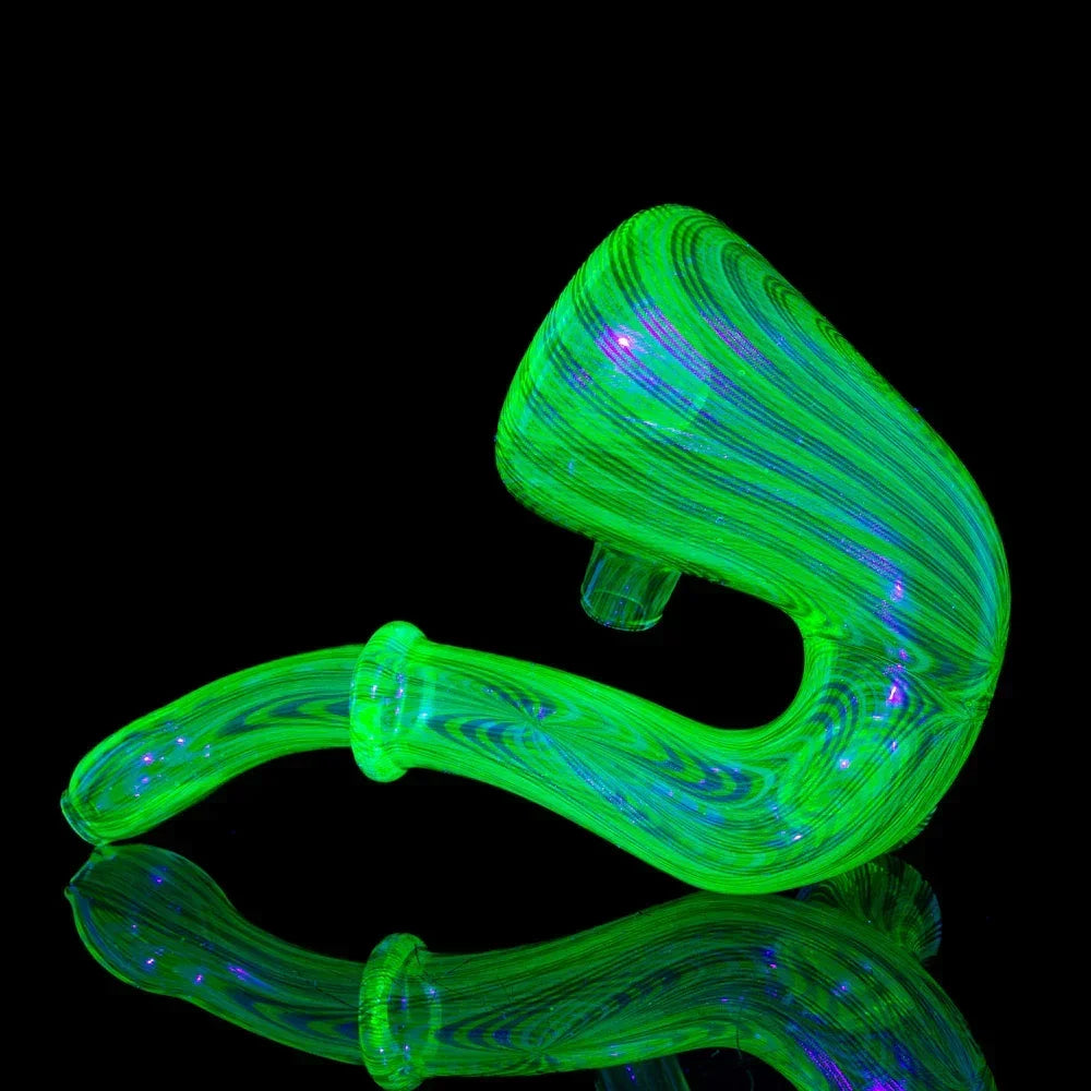 UV reactive green glass hand pipe with swirl design on a black reflective surface
