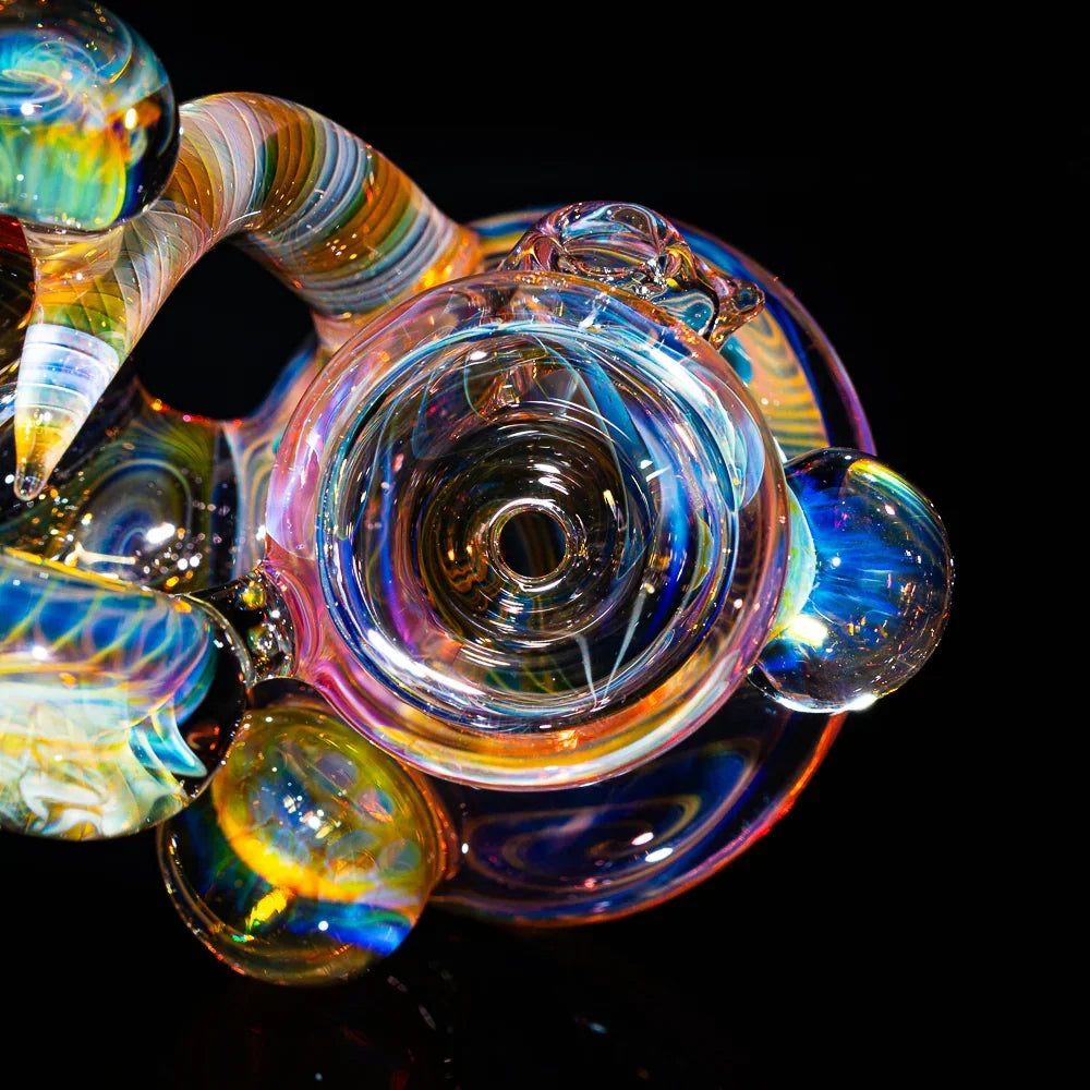 Colorful heady glass art pipe with intricate fume designs against a black background