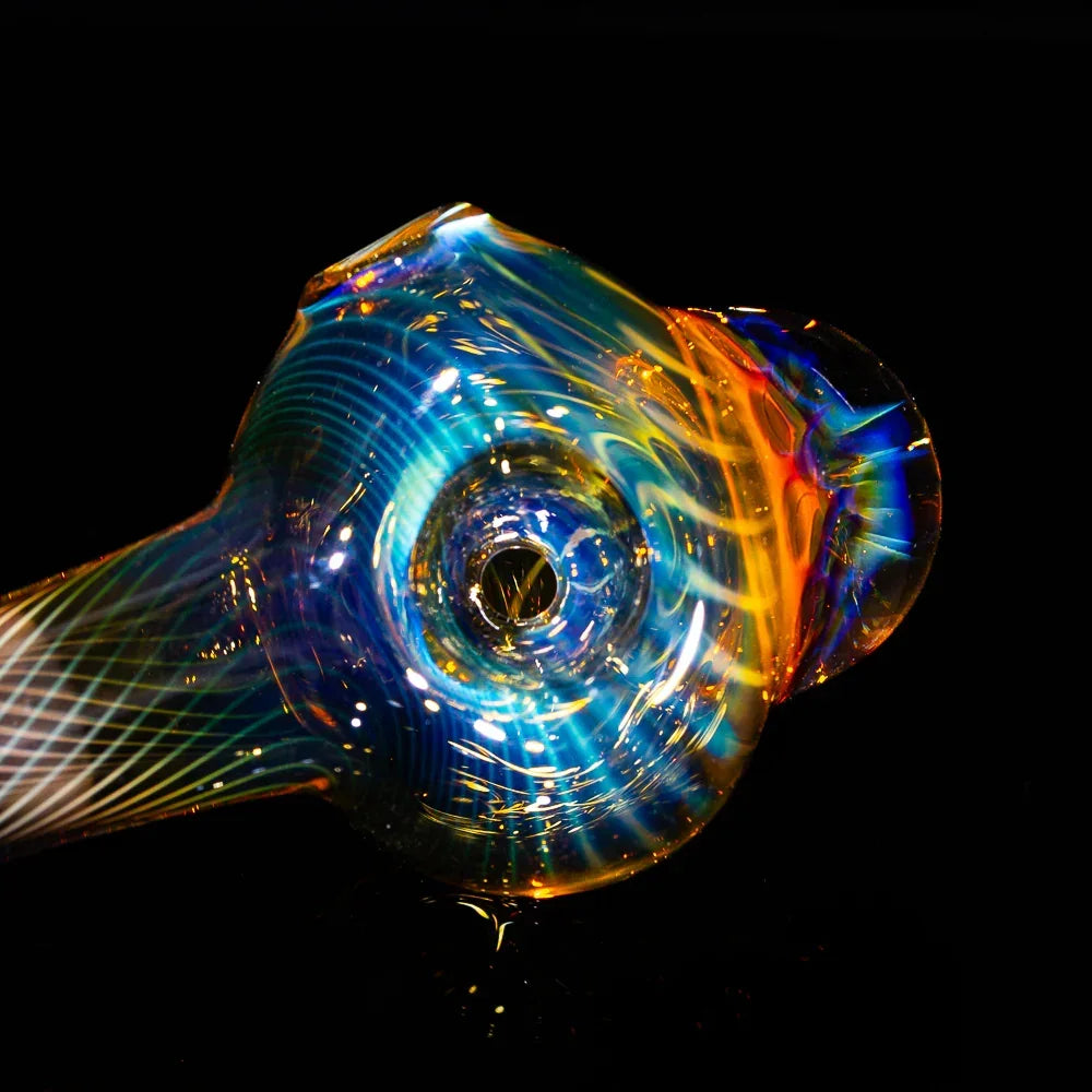 Iridescent honeycomb fumed glass spoon pipe with swirl patterns on a black background
