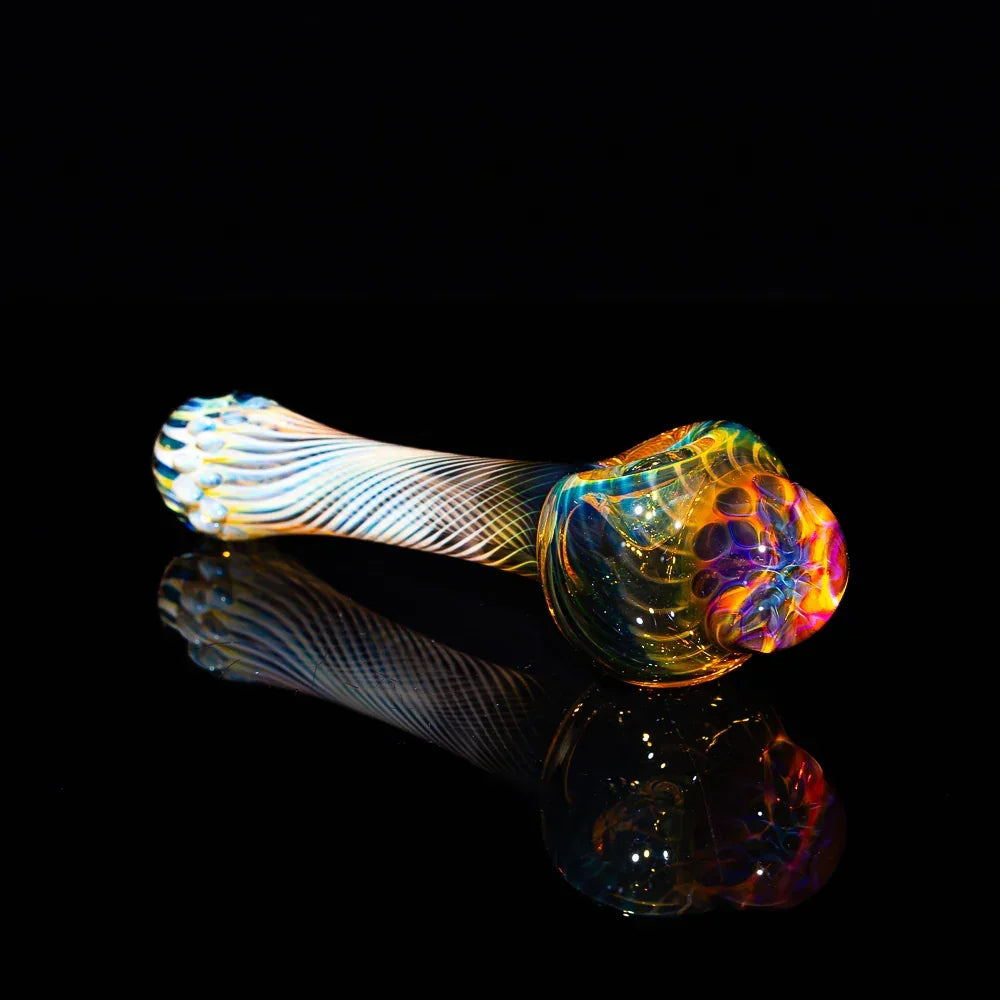 Colorful glass hand pipe with honeycomb fume design on a reflective black surface