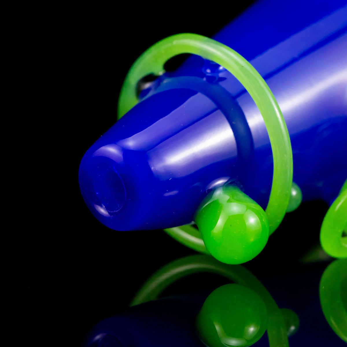 Blue glass hand pipe with neon green accents on a black reflective surface