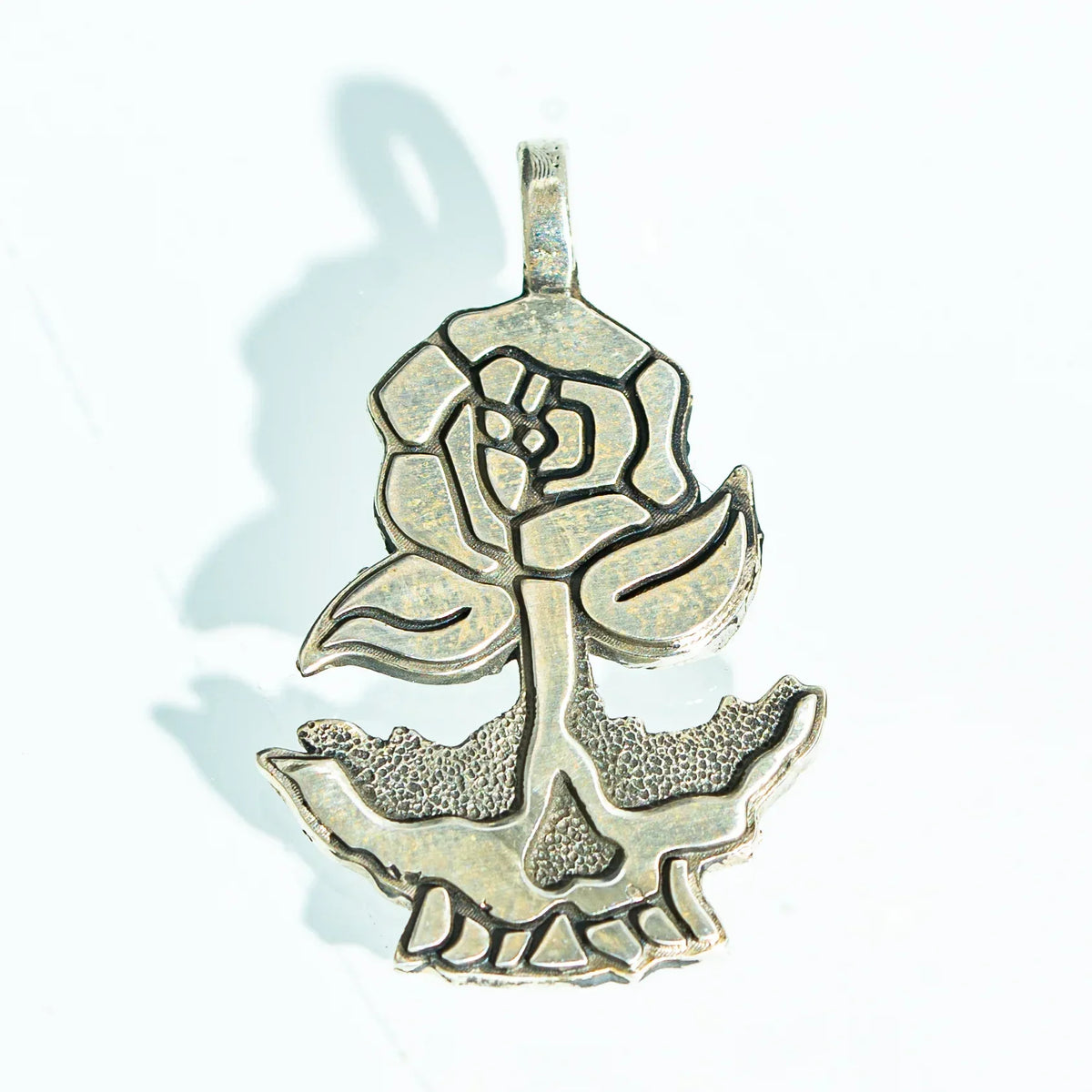 Silver pendant with rose and skull design on a white background, jewelry accessory