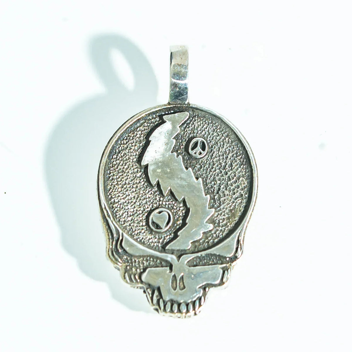 Silver skull pendant with yin yang and peace symbols, textured background, jewelry accessory