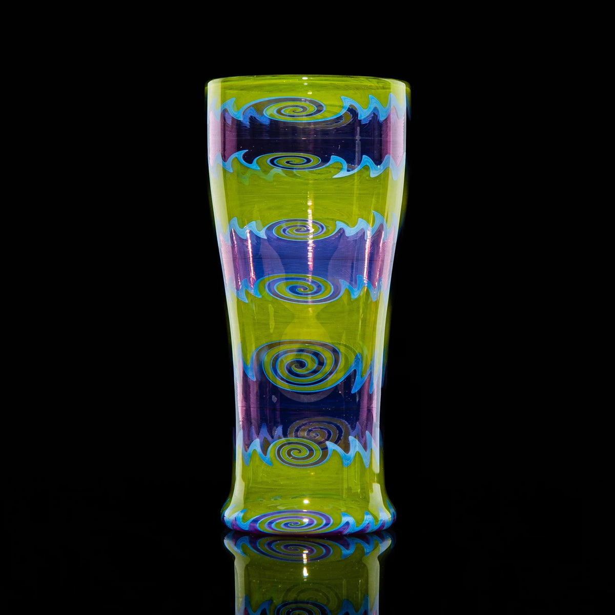 Purple and green glass wig wag cup with spiral and wave patterns on black background