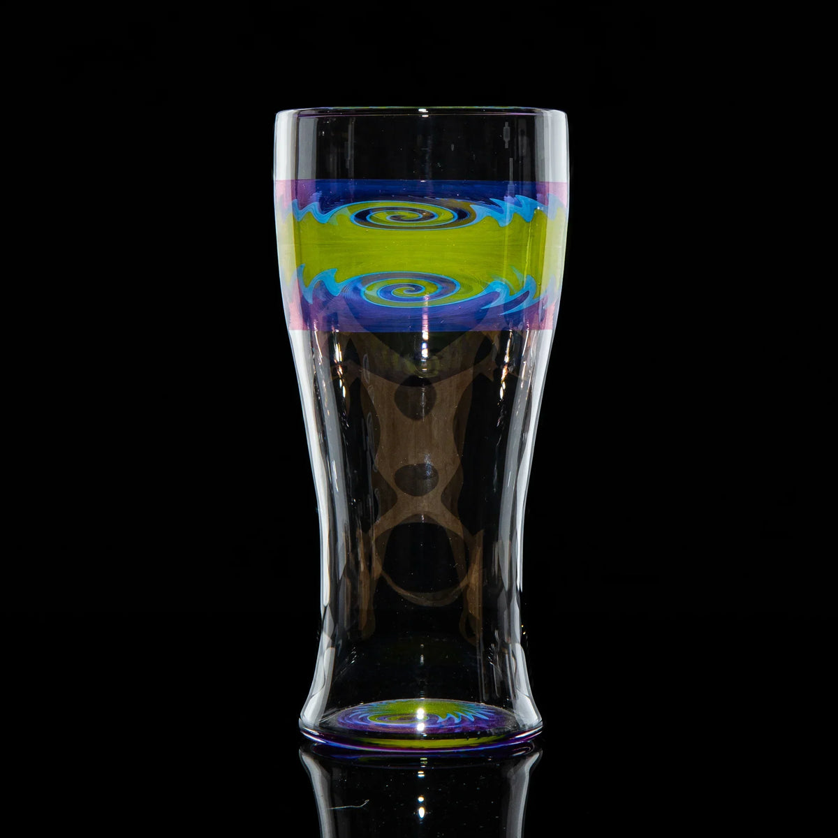Handblown glass cup with purple and green wig wag swirl design against black background