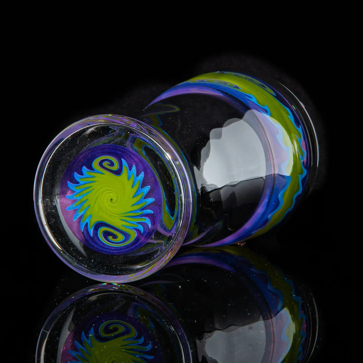 Hand-blown glass cup with purple and green wig wag pattern, reflective black background