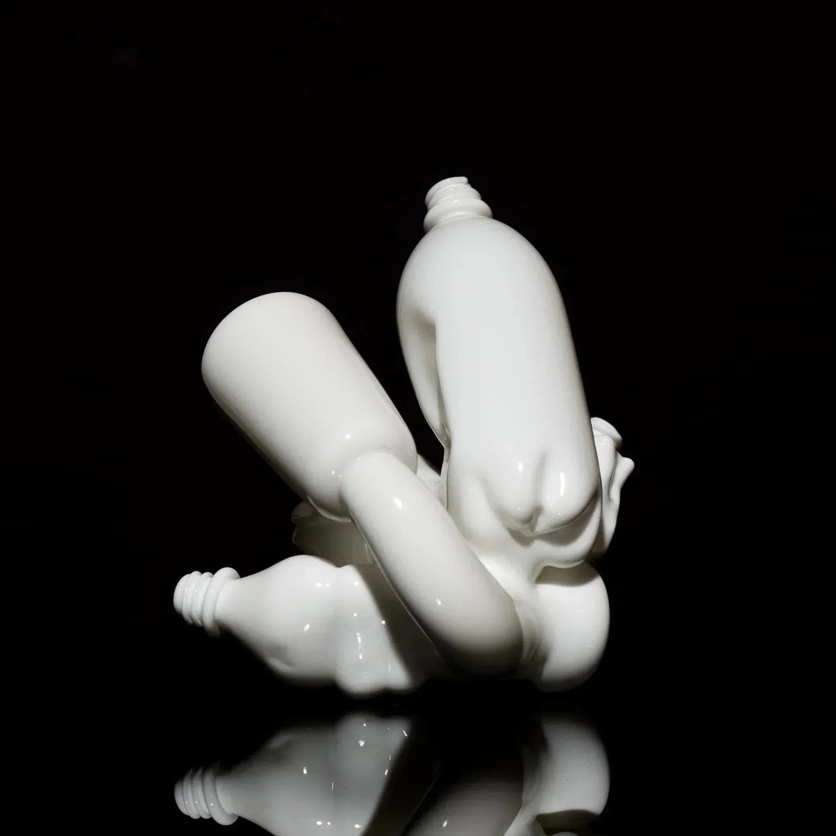 Abstract white glass art sculpture with smooth curves on a black reflective surface.