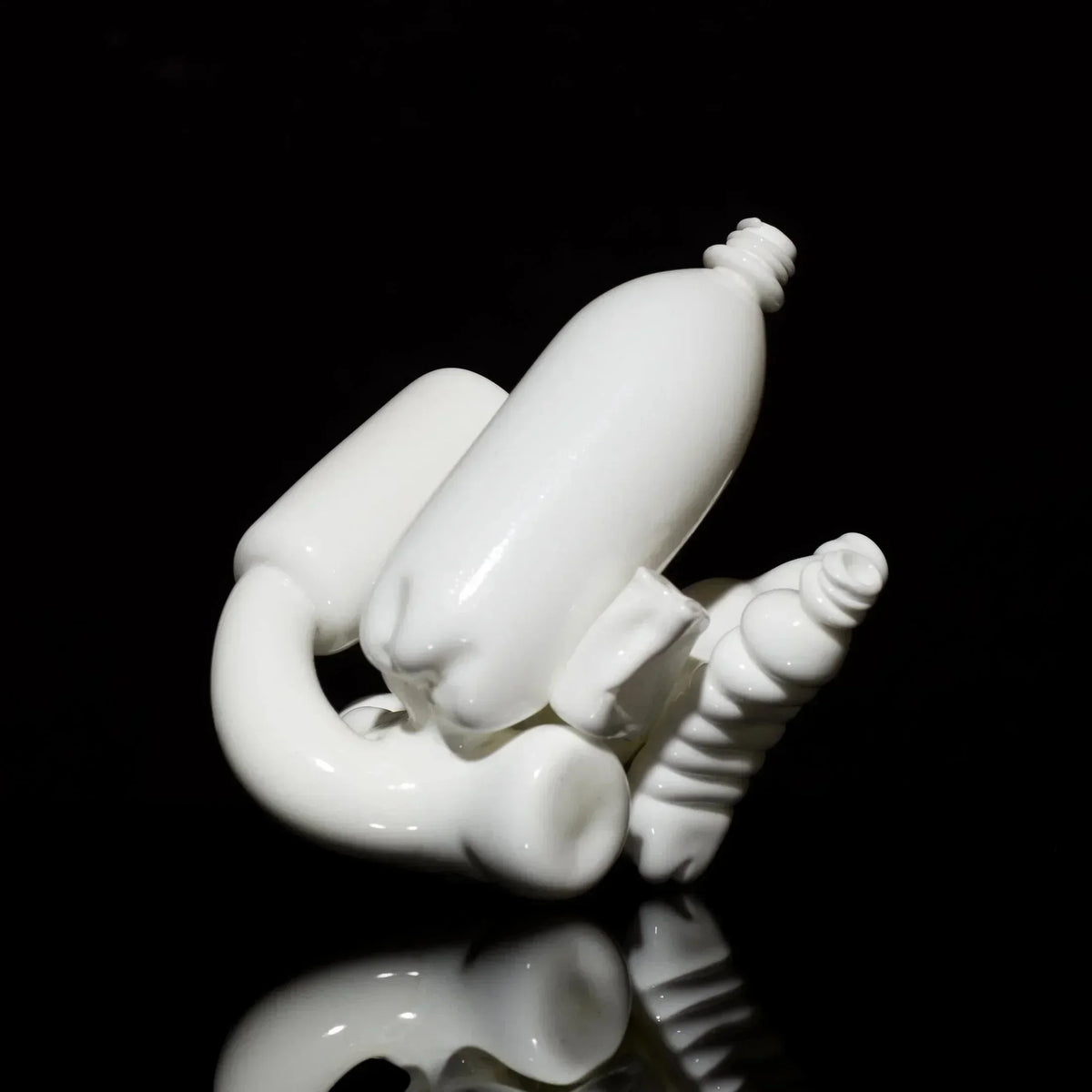 Unique white glass art pipe with intricate sculpted shapes on a black reflective surface
