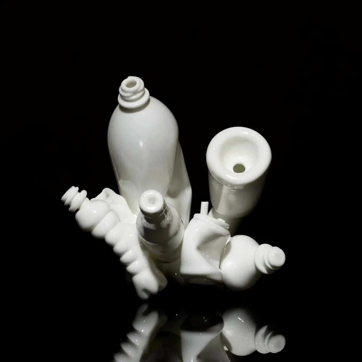White sculpted glass pipe with abstract, intricate design on black reflective surface
