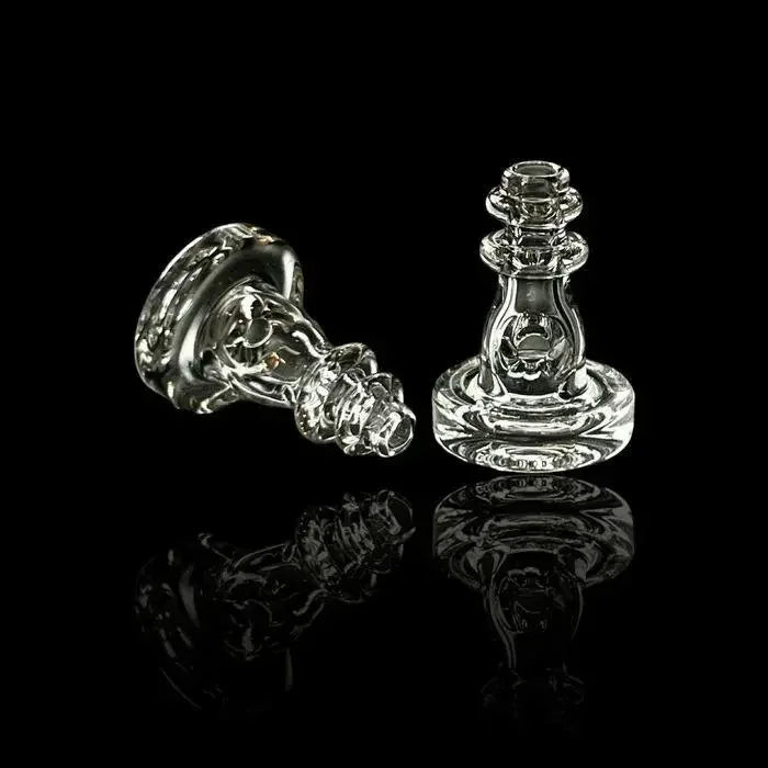Two clear glass carb caps with intricate design on black reflective surface