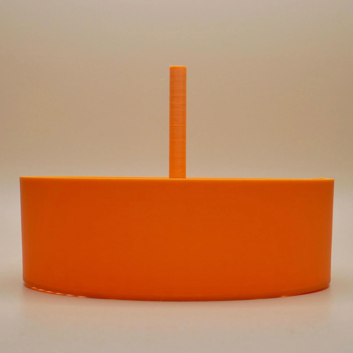 Bright orange cylindrical plastic accessory with central vertical handle, displayed on plain background