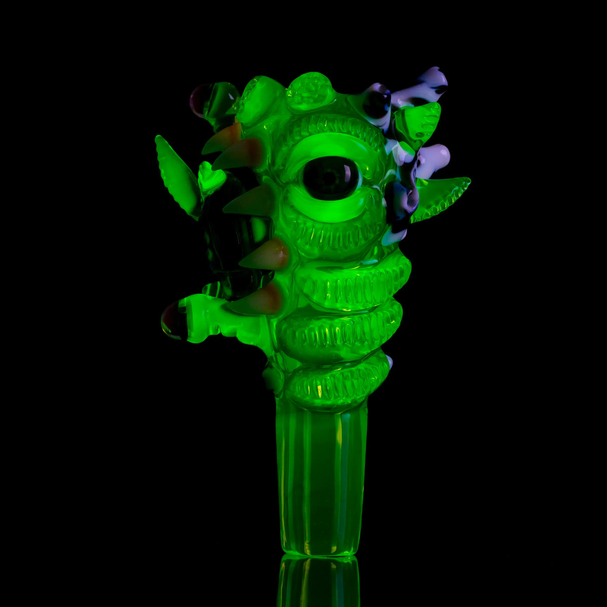 Glowing green glass slide with artistic monster design and three holes on black background