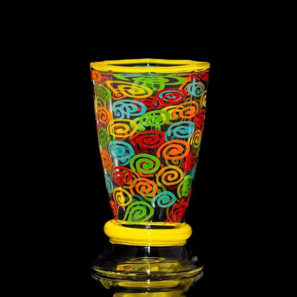 Colorful hand-blown glass cup with vibrant swirl patterns on black background