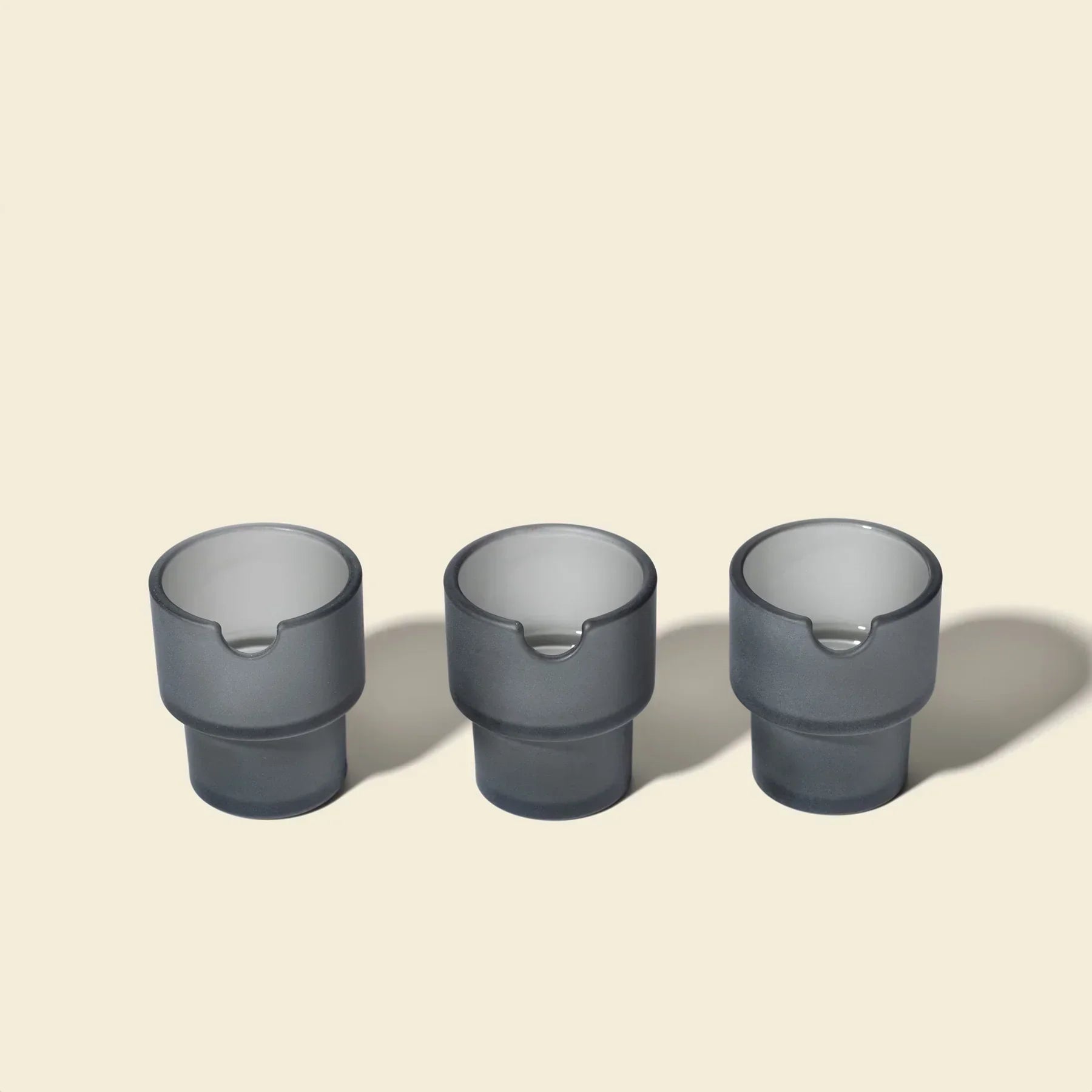Three charcoal gray glass bowls with notches, displayed on a light background.