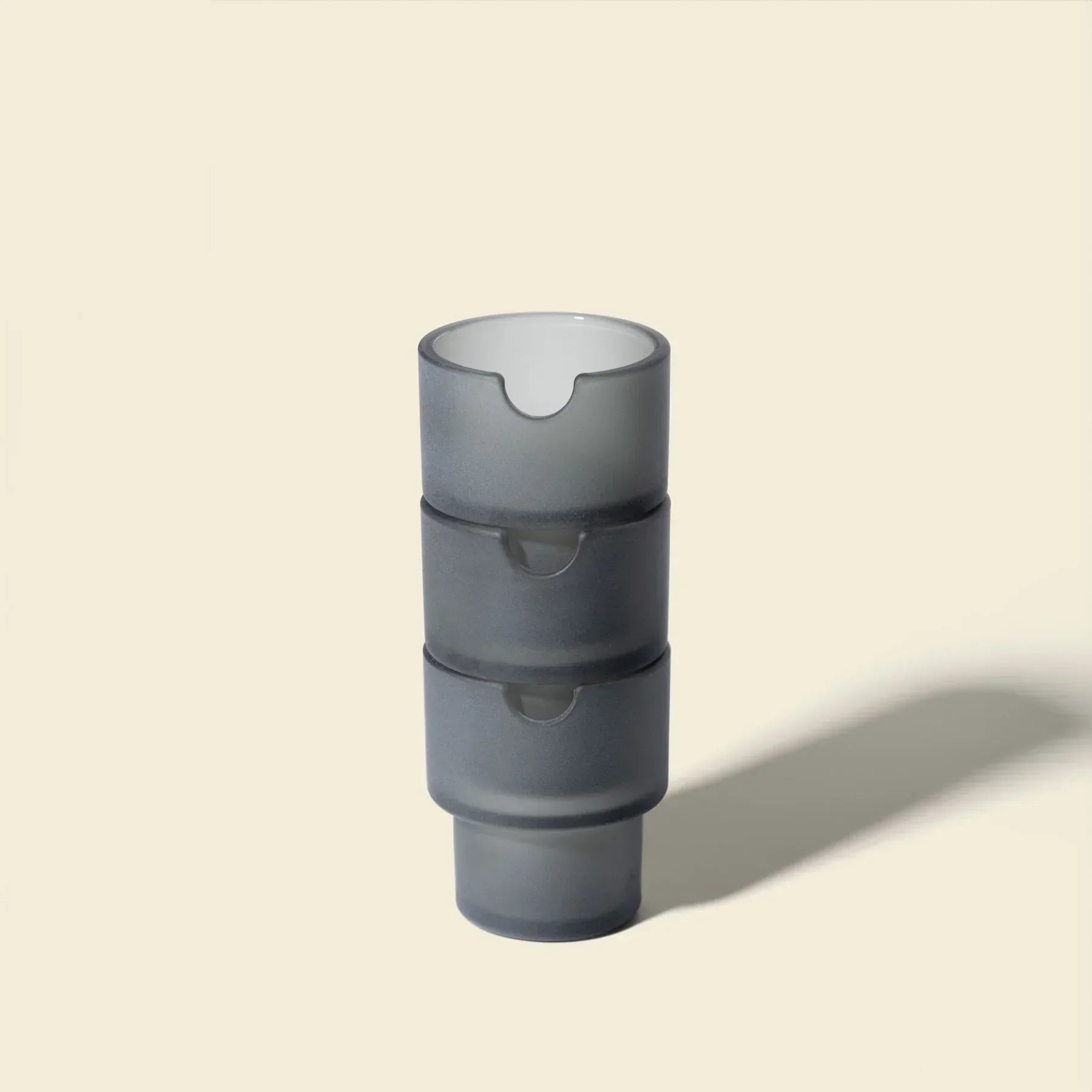 Stacked charcoal gray glass ashtrays with a modern minimalist design on neutral background.