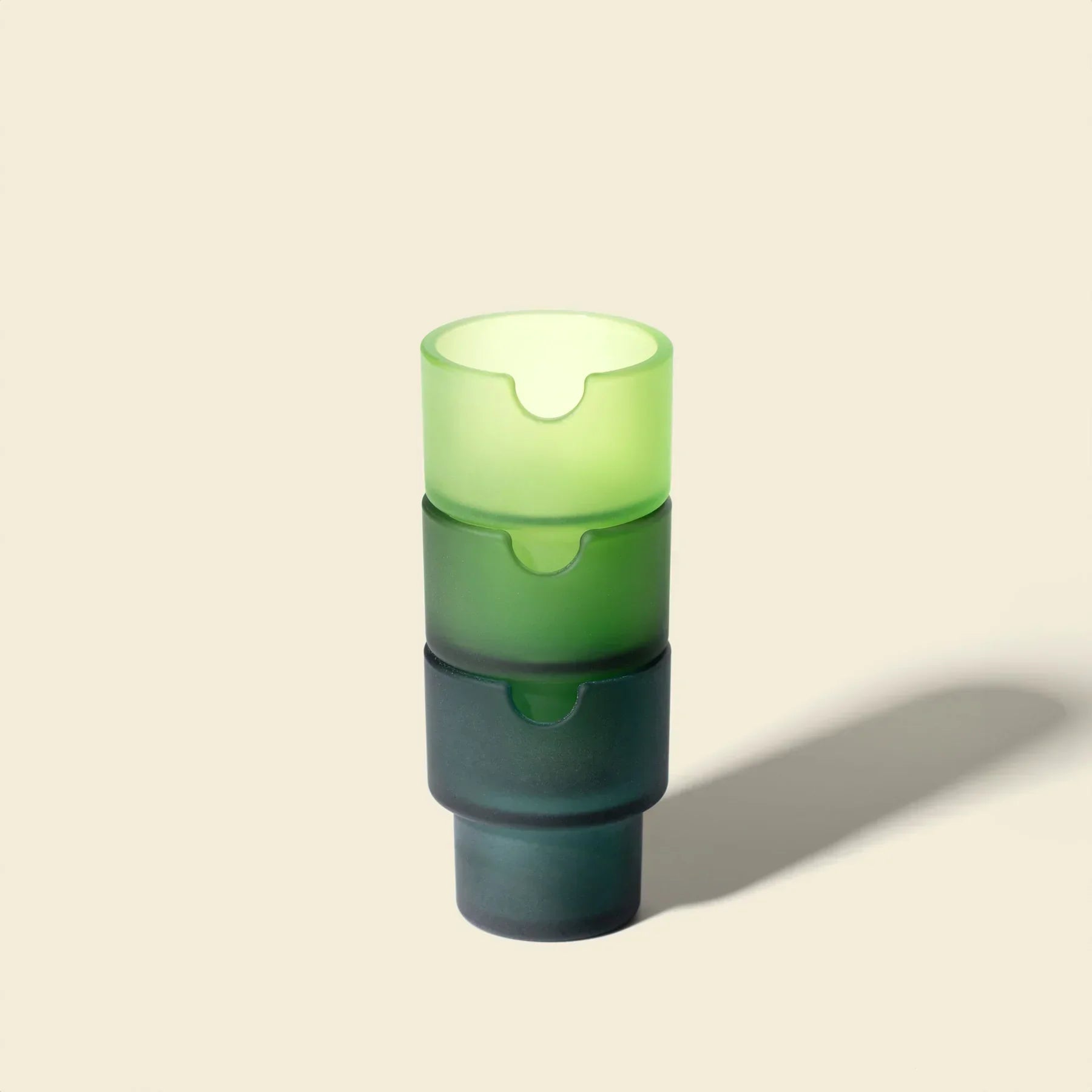 Stacked green frosted glass ashtrays on a neutral background