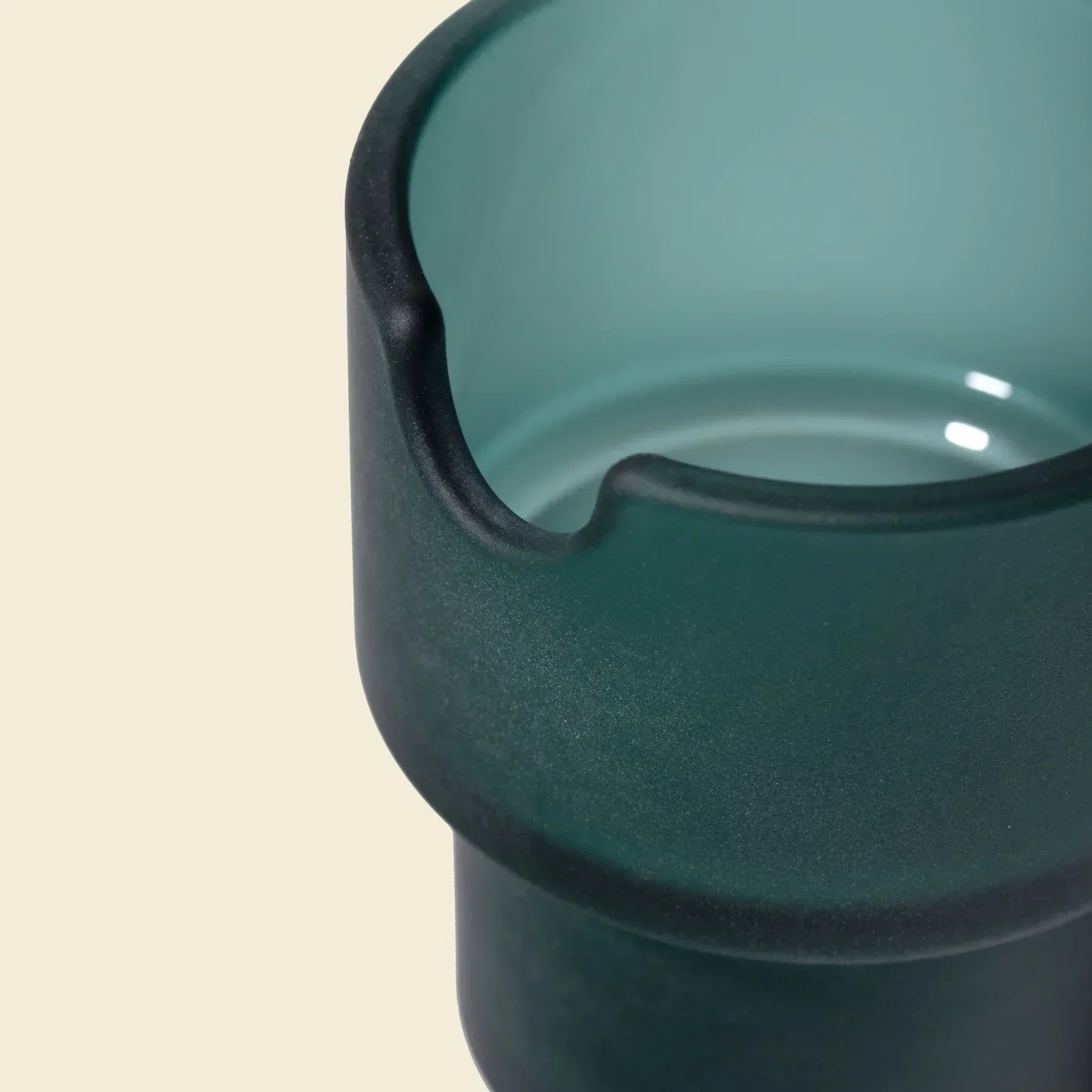 Close-up of a modern green glass flowerpot with smooth matte finish and notch detail