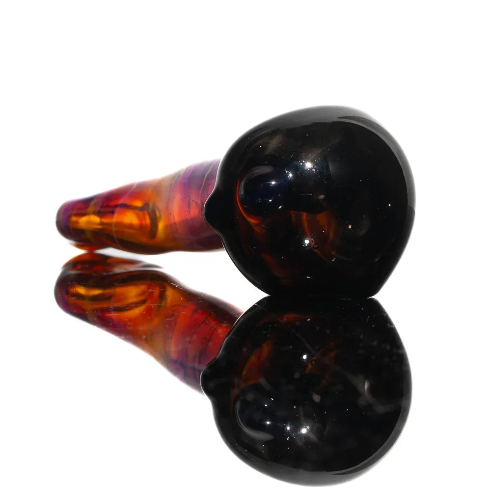 Hand-blown amber and purple glass spoon pipe with reflective surface display.