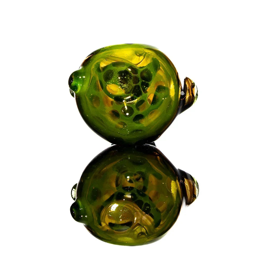 Green glass spoon pipe with honeycomb pattern on a reflective surface