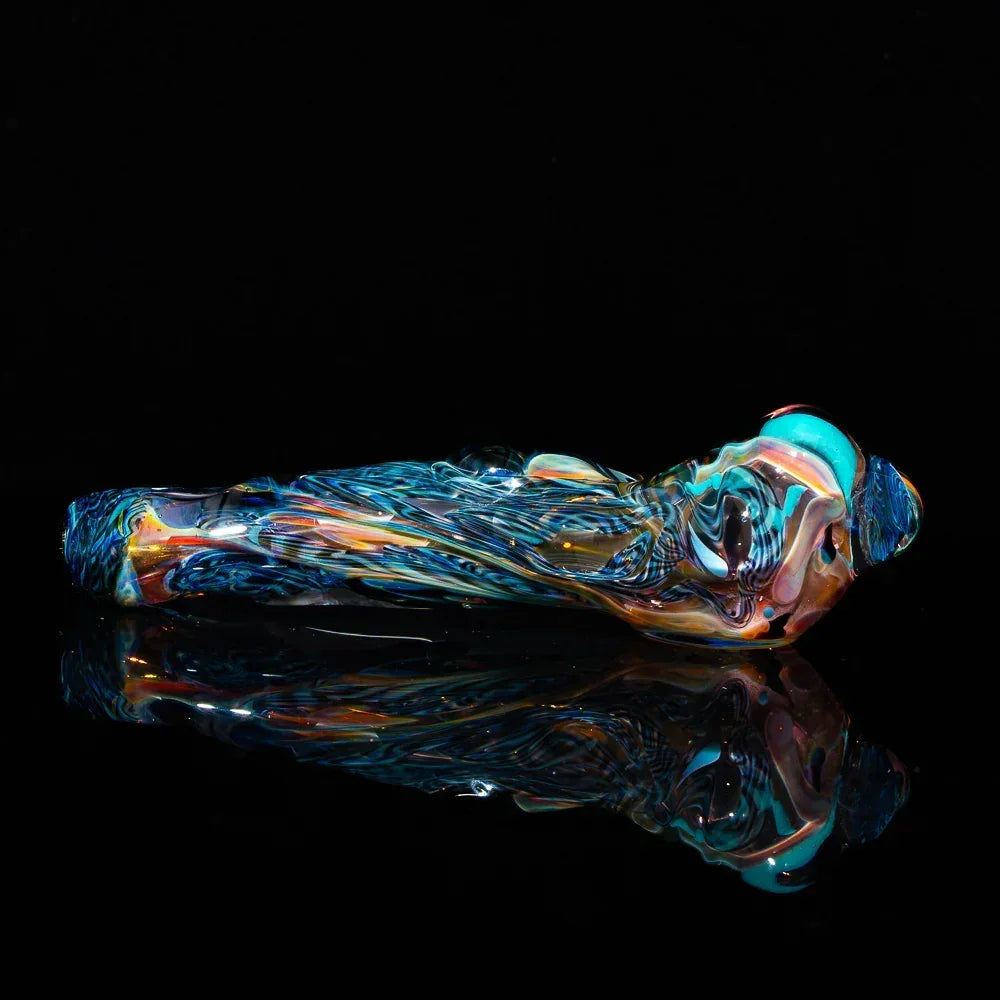 Colorful glass art hand pipe with fumed, inside-out swirling patterns on black background
