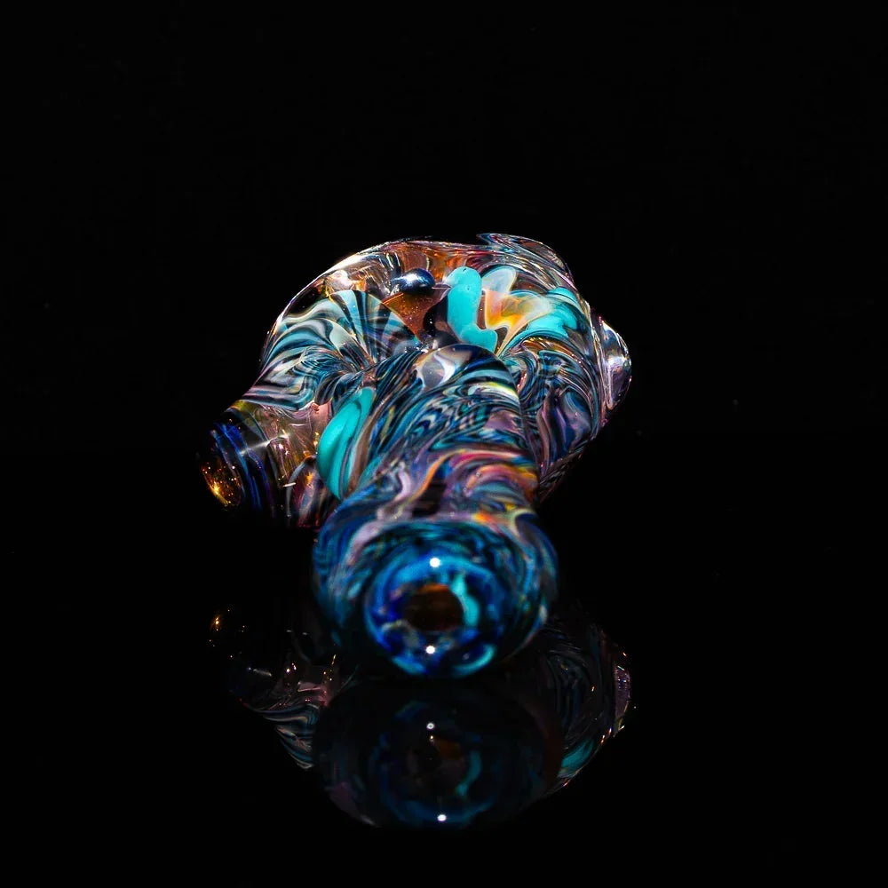 Colorful fumed glass art spoon pipe with swirled patterns on a black background