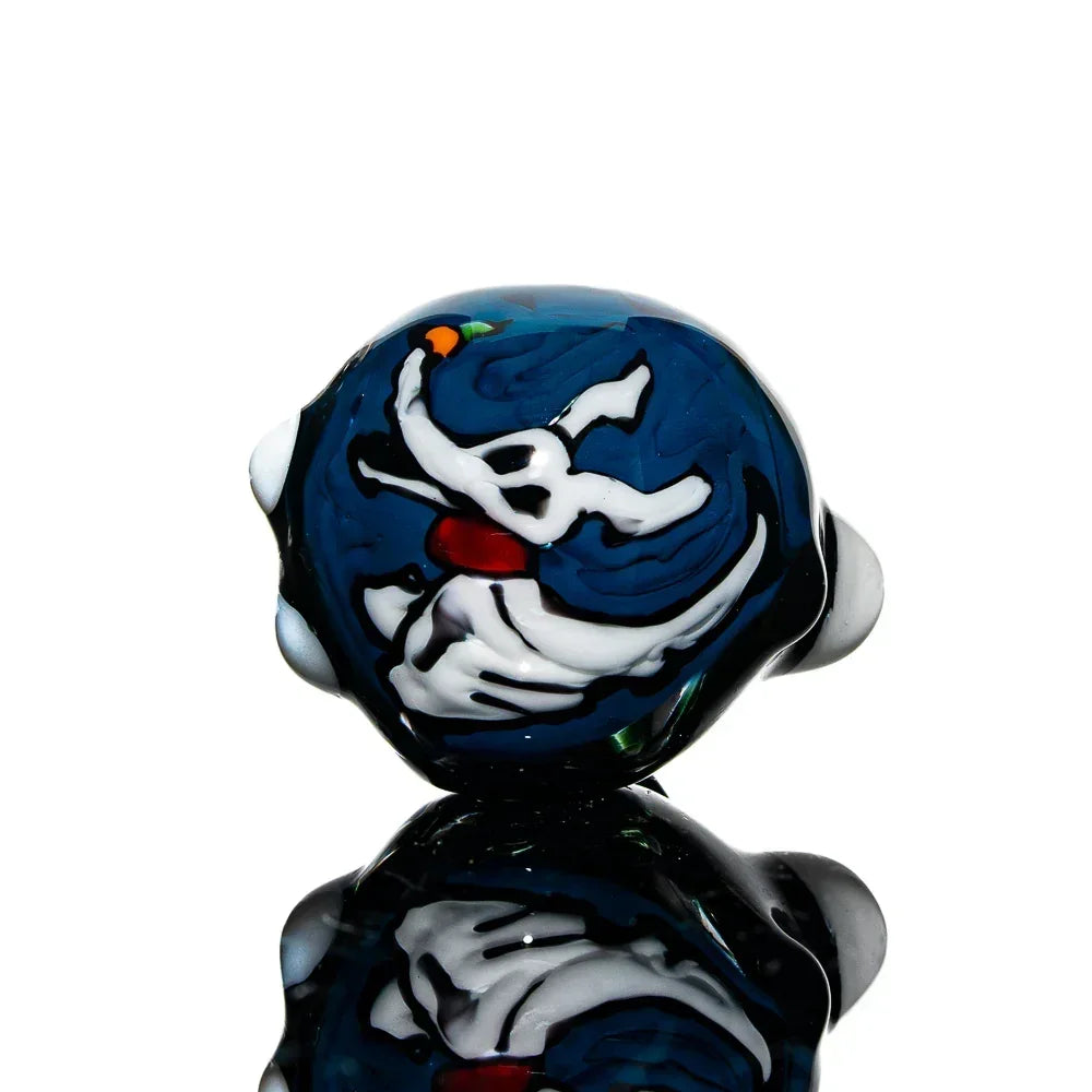 Handcrafted glass spoon pipe with white dog art on deep blue background, reflective surface