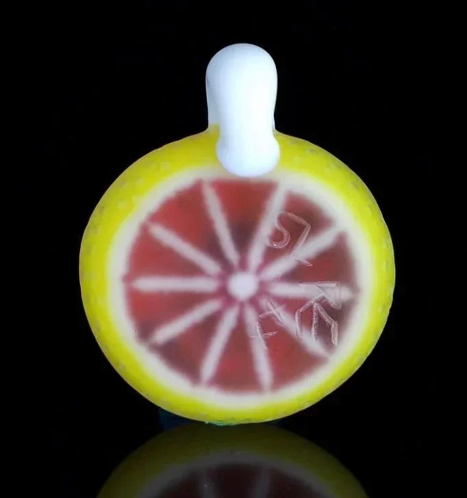 Glass carb cap shaped like a citrus slice with yellow, white, and red detailing