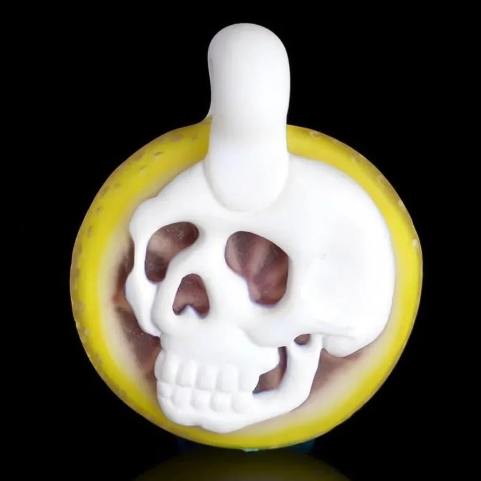 Heady glass carb cap shaped like a white skull with yellow trim on black background