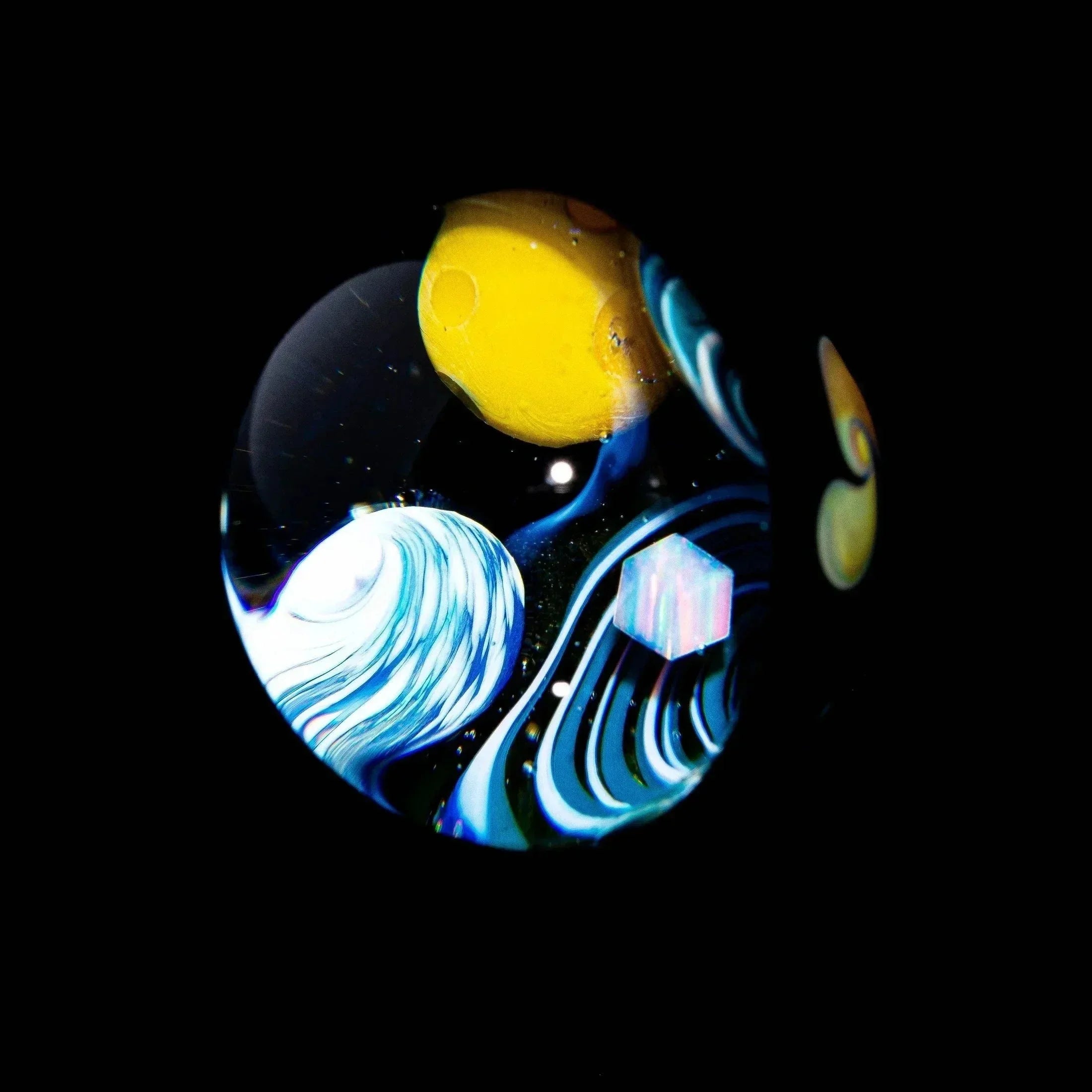 Heady glass marble with colorful abstract galaxy and wave design on black background.