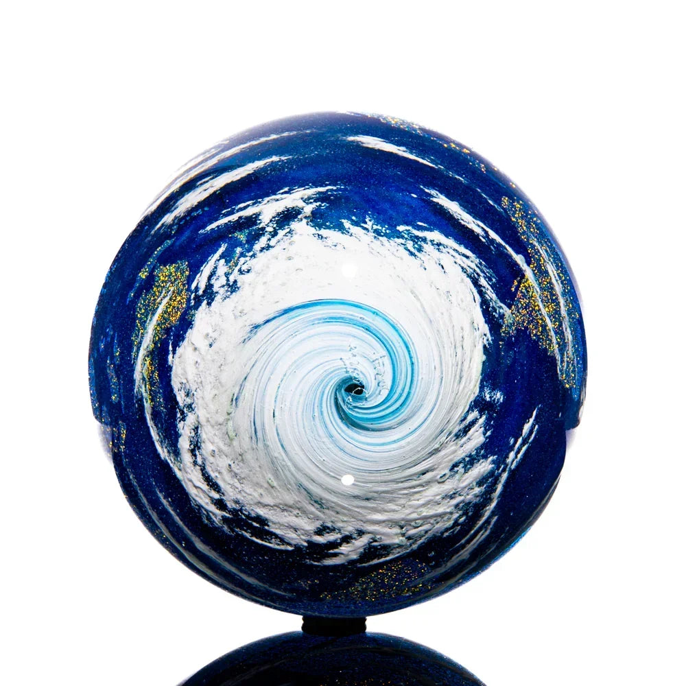 Hand-blown glass marble with swirling blue and white Earth design, vortex pattern center
